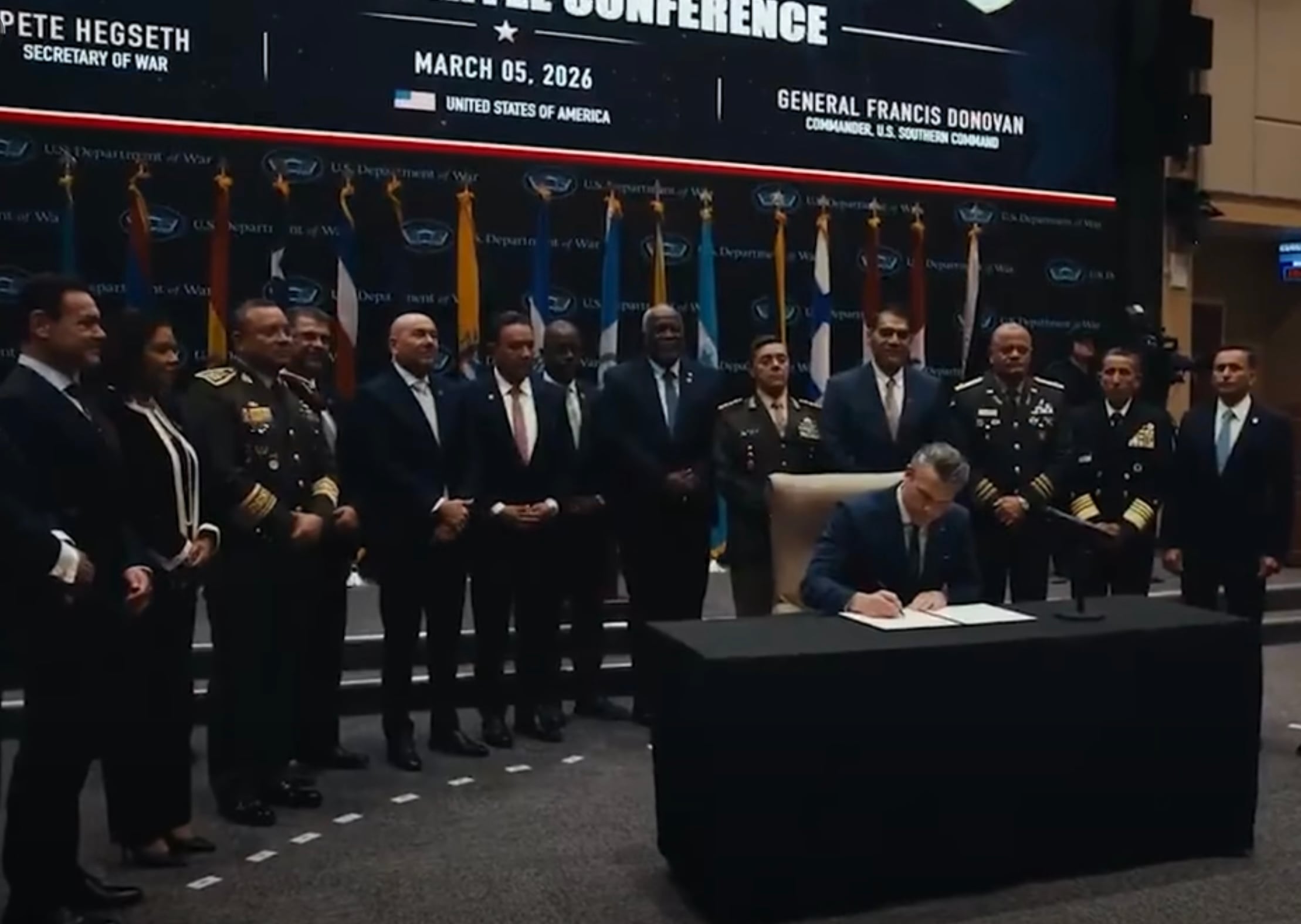 El ministro de Seguridad Pública de Costa Rica, Mario Zamora, (cuarto de izq. a der.) observa mientras Pete Hegseth, secretario de Guerra de Estados Unidos, firma la Declaración Conjunta de Seguridad de la Conferencia de las Américas contra los Carteles, el 5 de marzo de 2026 en Doral, Florida. La escena fue captada en un video difundido por el propio Departamento de Guerra estadounidense.
