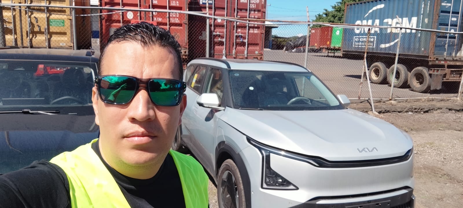 Sergio Barahona frente a un Kia EV5 Land eléctrico blanco en el puerto de Caldera, Costa Rica, como parte del proceso de importación desde China mediante Alibaba.
