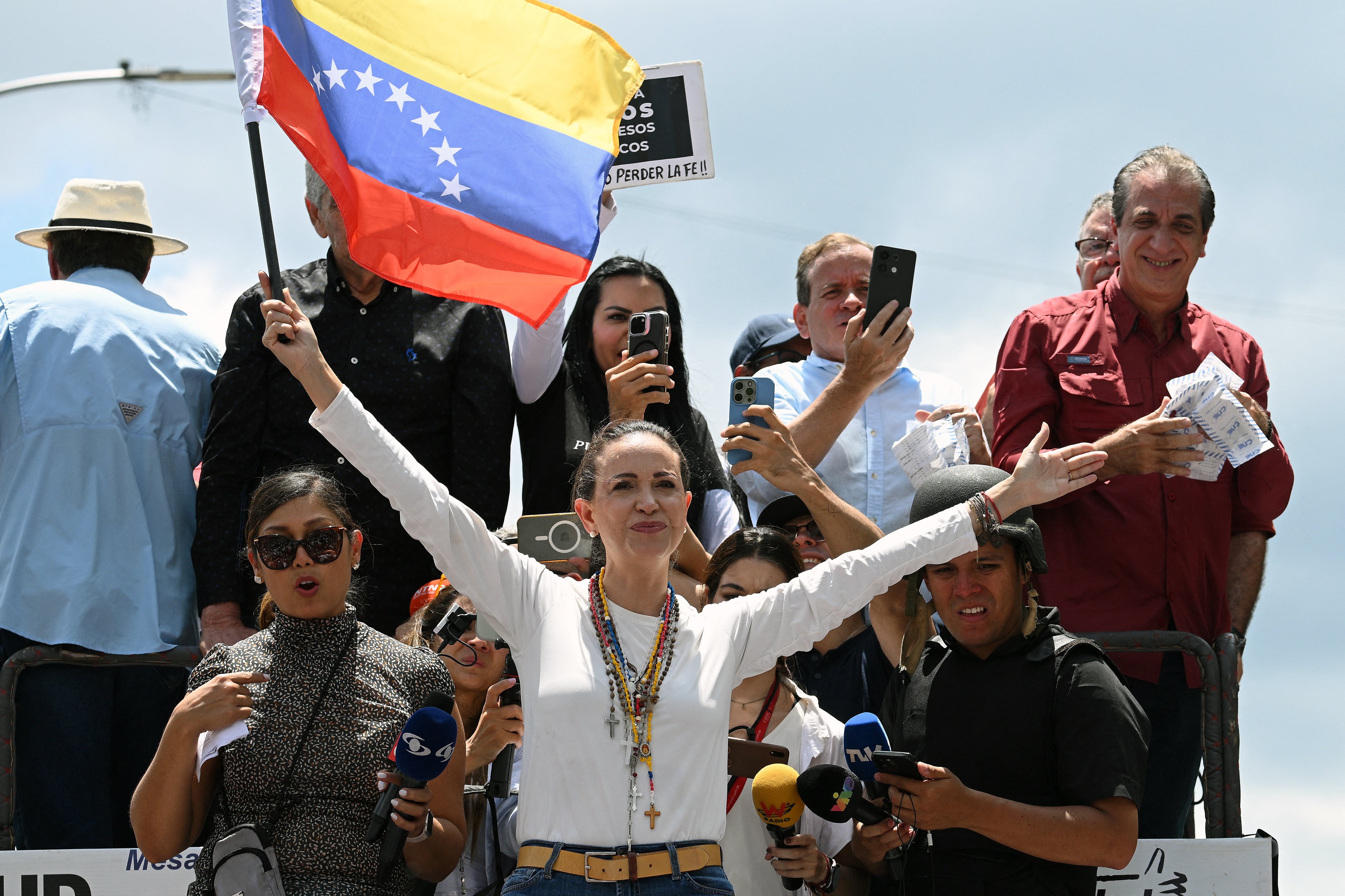 La líder opositora venezolana María Corina Machado (centro) con una bandera nacional sobre un camión durante una protesta convocada por la oposición para que se reconozca la victoria electoral, en Caracas, el 17 de agosto de 2024. Fotografía: