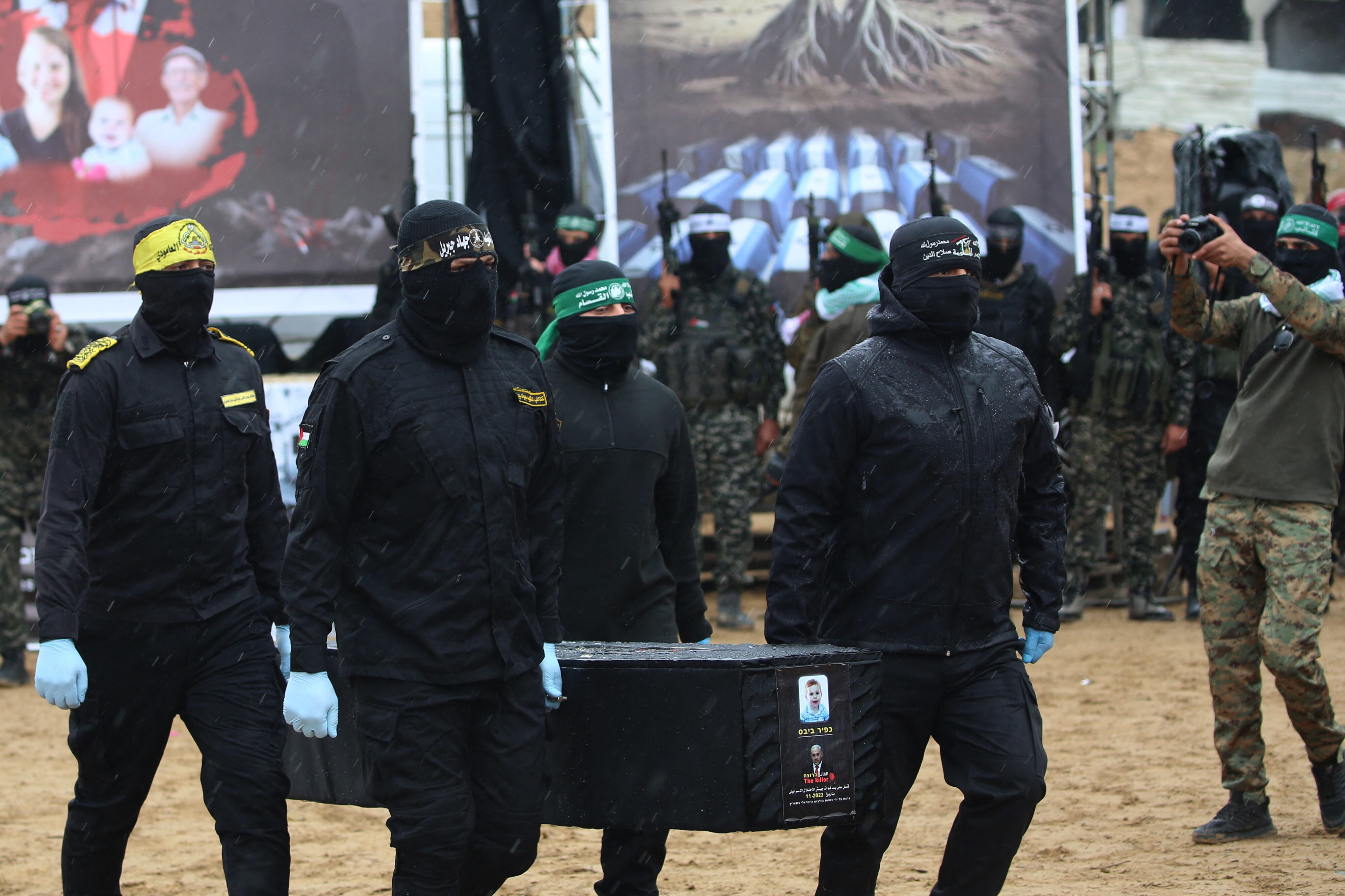 Hamas militants take pictures as fellow masked Palestinian fighters carry one of the coffins during the handover of the bodies of four Israeli hostages to the Red Cross in Khan Yunis in the southern Gaza on February 20, 2025. Hamas handed over on F