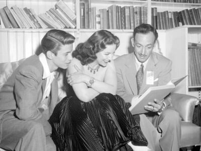 Jorge Negrete y María Félix con el hijo de la actriz observando un libro en una sala, un retrato de la vida familiar del icónico cantante y actriz del cine mexicano.