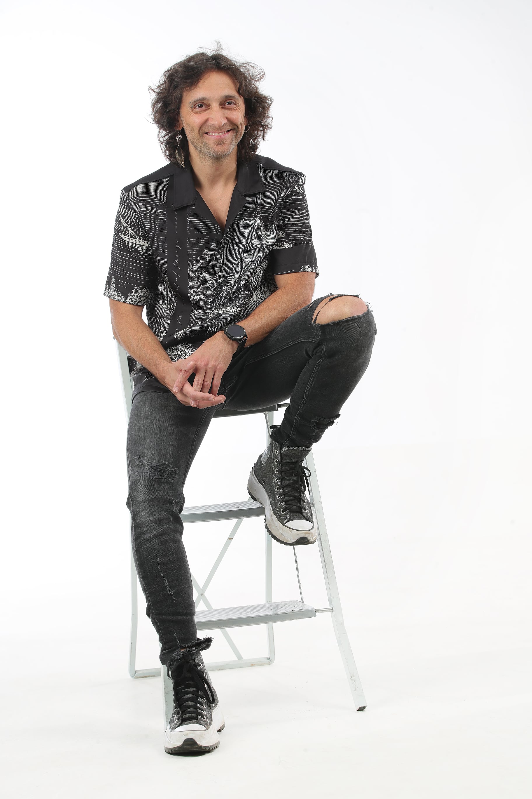 Retrato del músico costarricense Luis Montalbert sentado en una escalera.