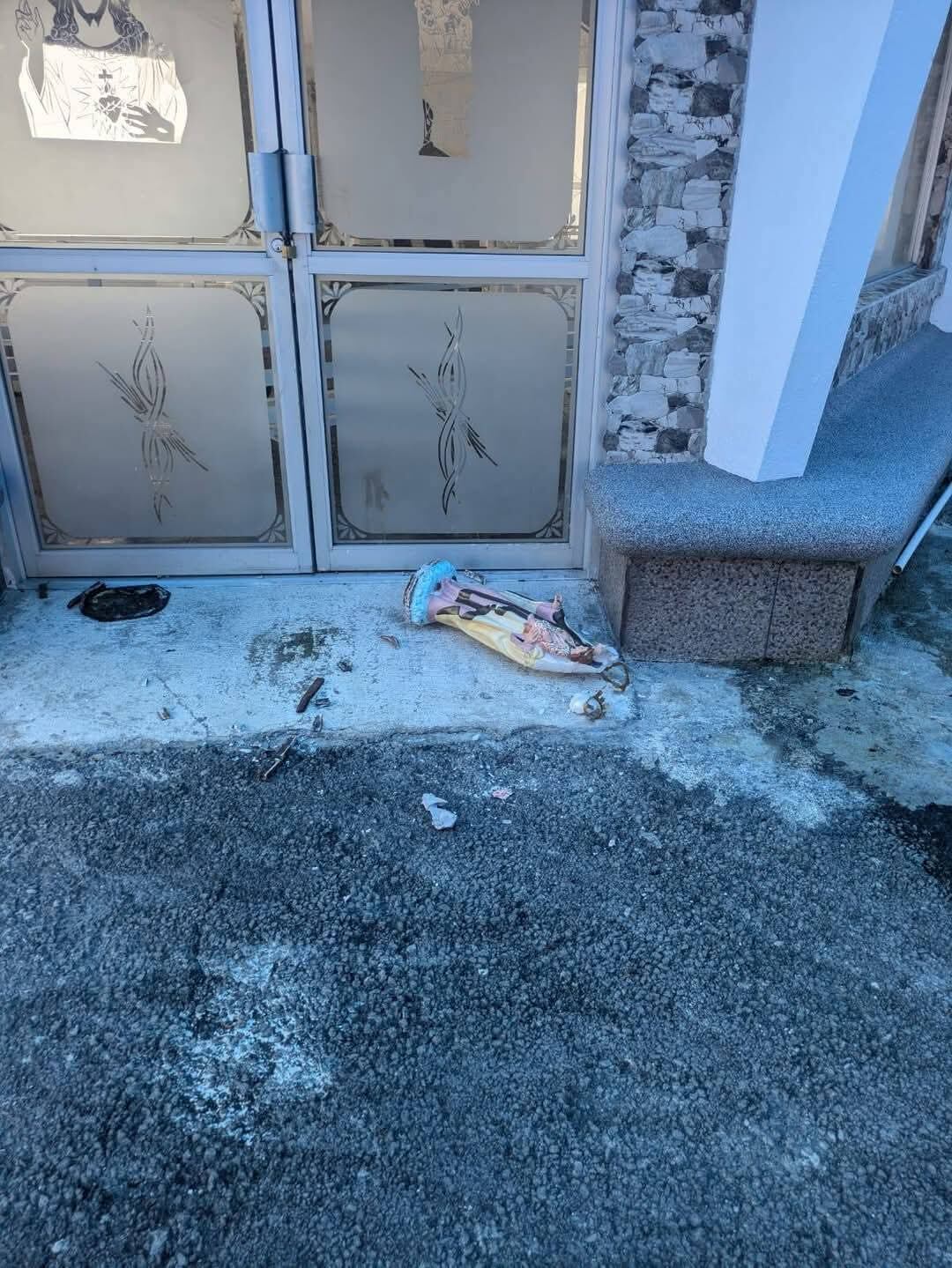 Imagen de la virgen, al frente de unas puertas de vidrio.