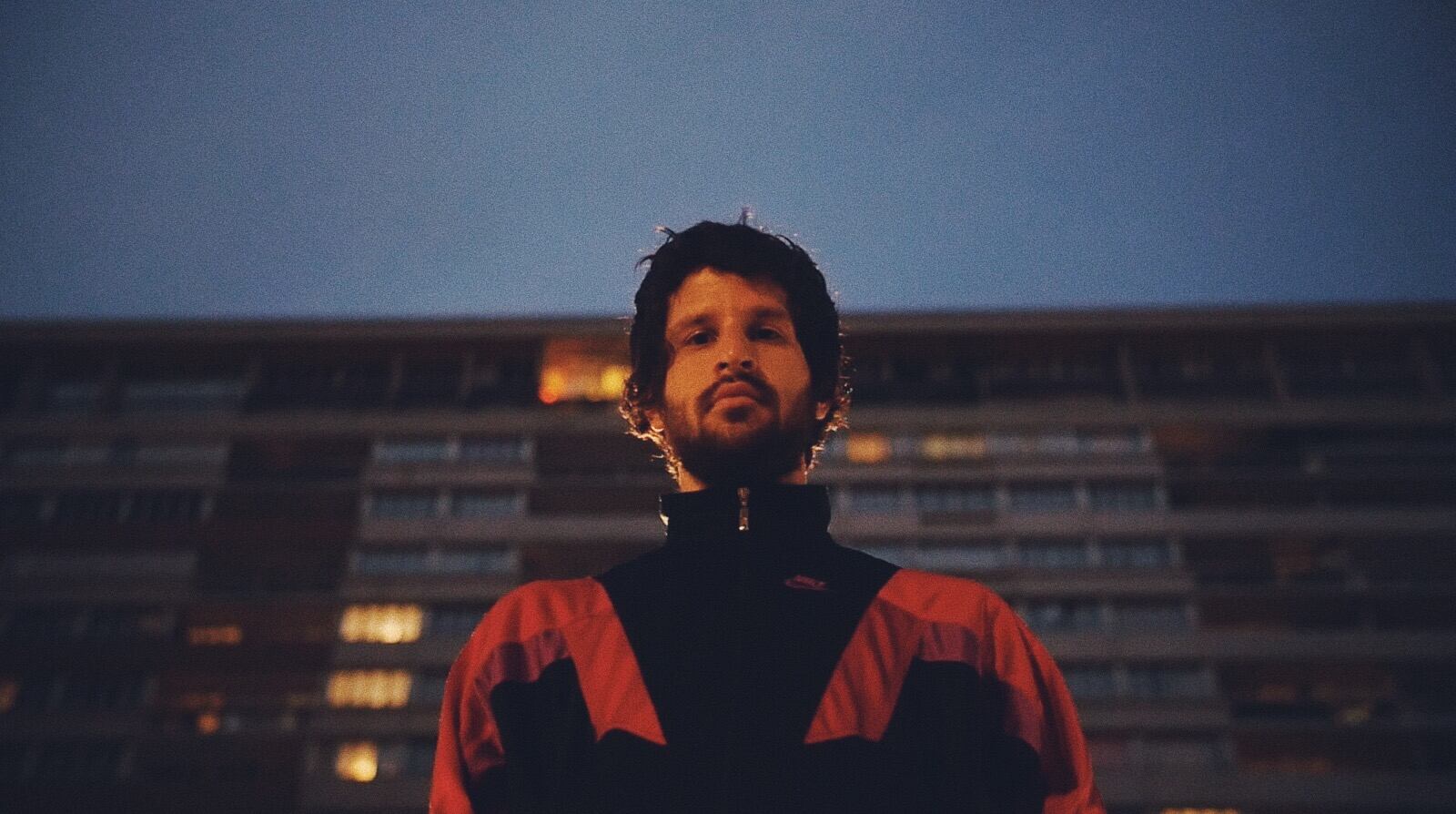 Imagen del músico costarricense Javier Arce de Cocofunka en primer plano. Viste una chaqueta negra con detalles en rojo.