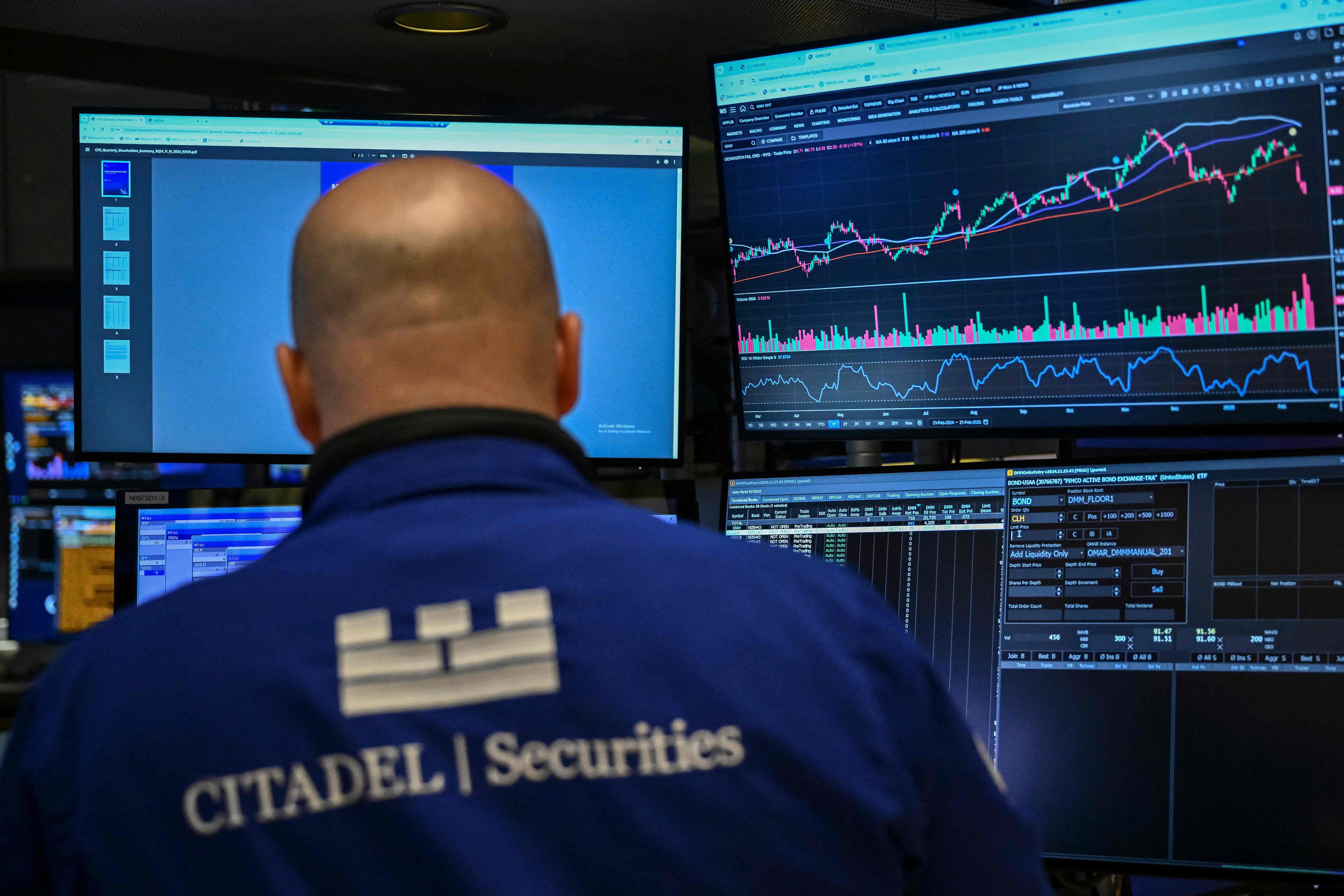 Operador de Citadel Securities observa gráficos del S&P 500 en la Bolsa de Nueva York, con datos de mercado en múltiples pantallas.