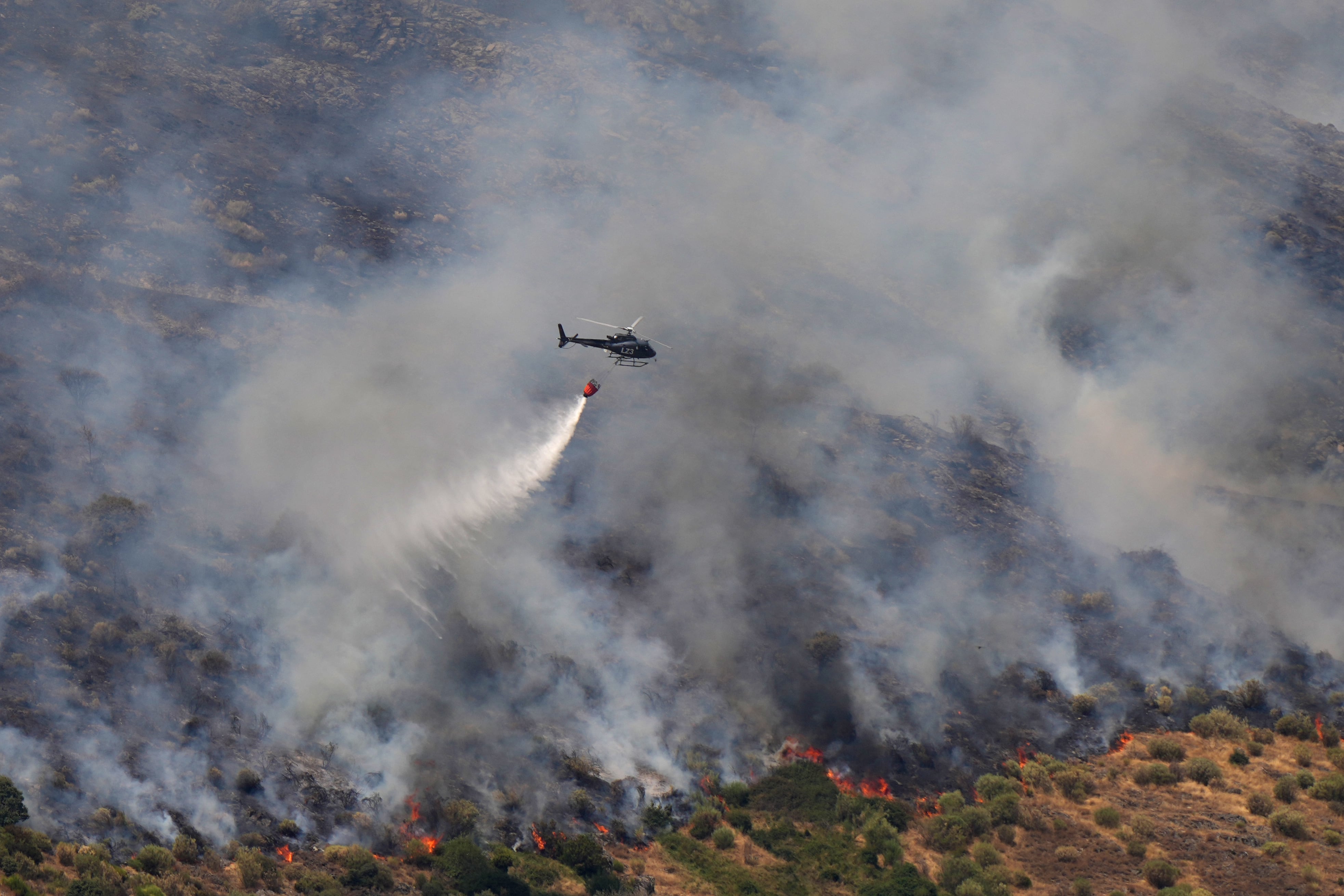 A helicopter fights a wildfire in Castrillo de Cabrera, northwestern Spain, on August 16, 2025. Spain, now in its third week under a heatwave alert, is still battling wildfires raging in the northwest and west of the country, where the army has been deployed to help contain the blazes. The regions of Castilla y Leon, Galicia, Asturias and Extr