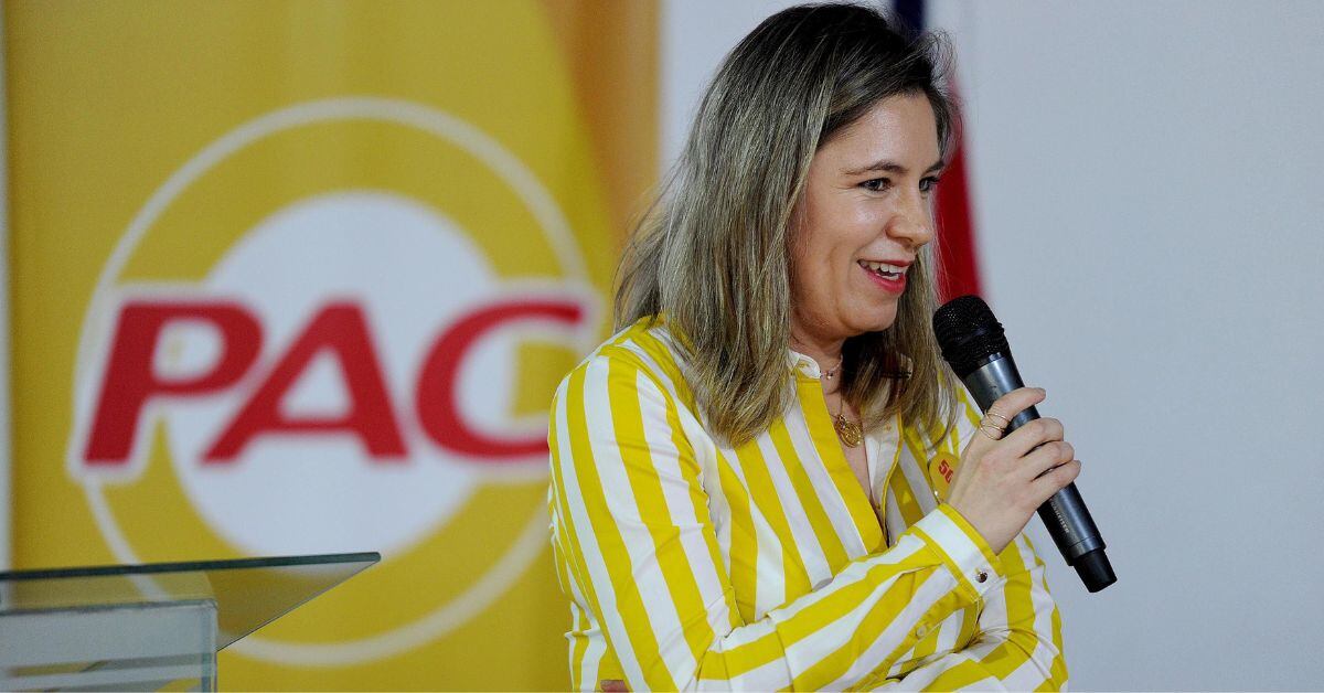 En la imagen, la exprimera dama, Claudia Dobles. Atrás hay un cartel que dice PAC.