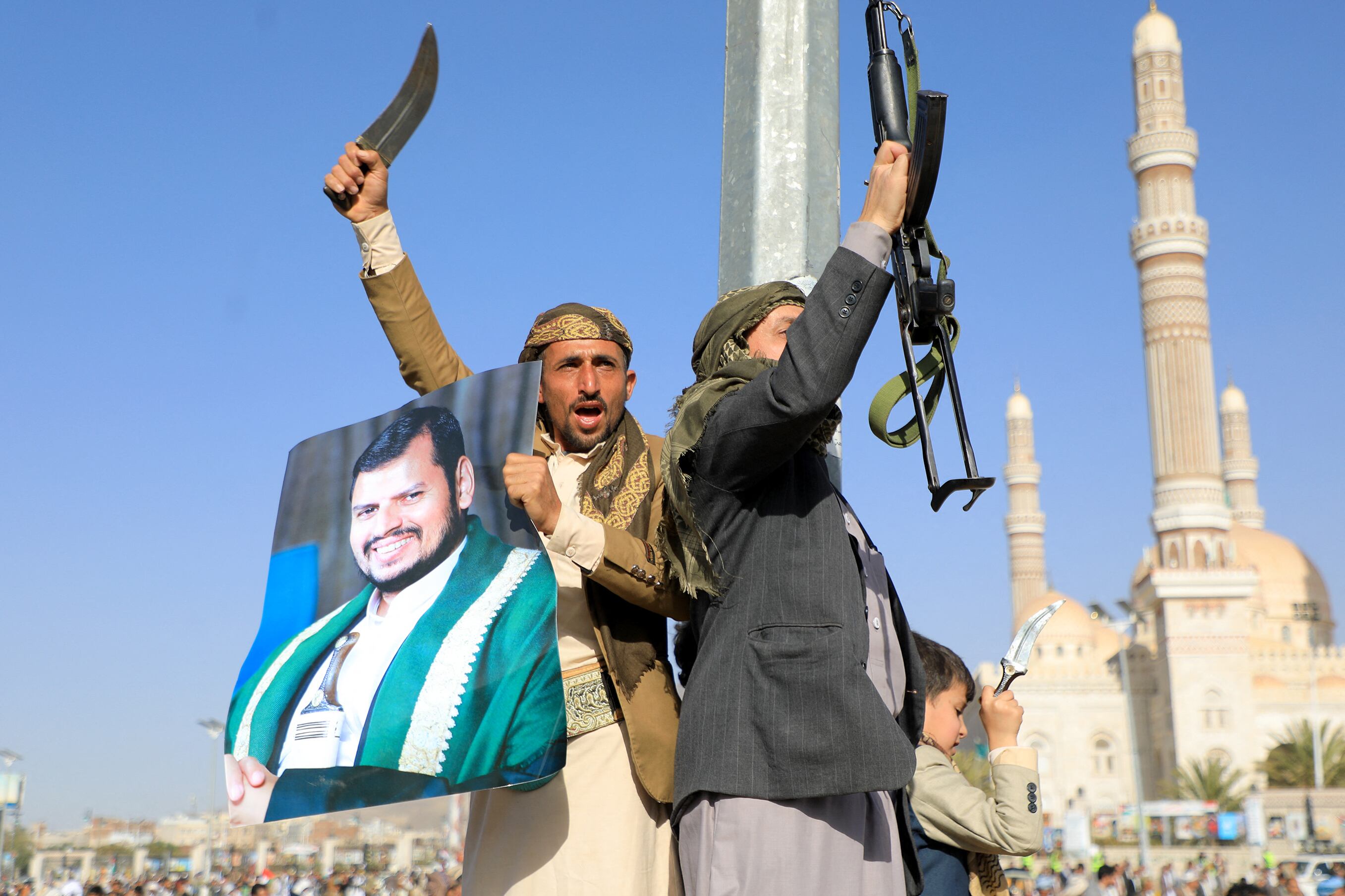 Combatientes hutíes, uno de ellos con un retrato del líder hutí Abdul Malik al-Houthi (izq.), blanden sus armas durante una protesta tras los ataques de las fuerzas estadounidenses y británicas, en Saná, la capital controlada por los hutíes, en medio de las batallas en curso entre Israel y Hamás.
