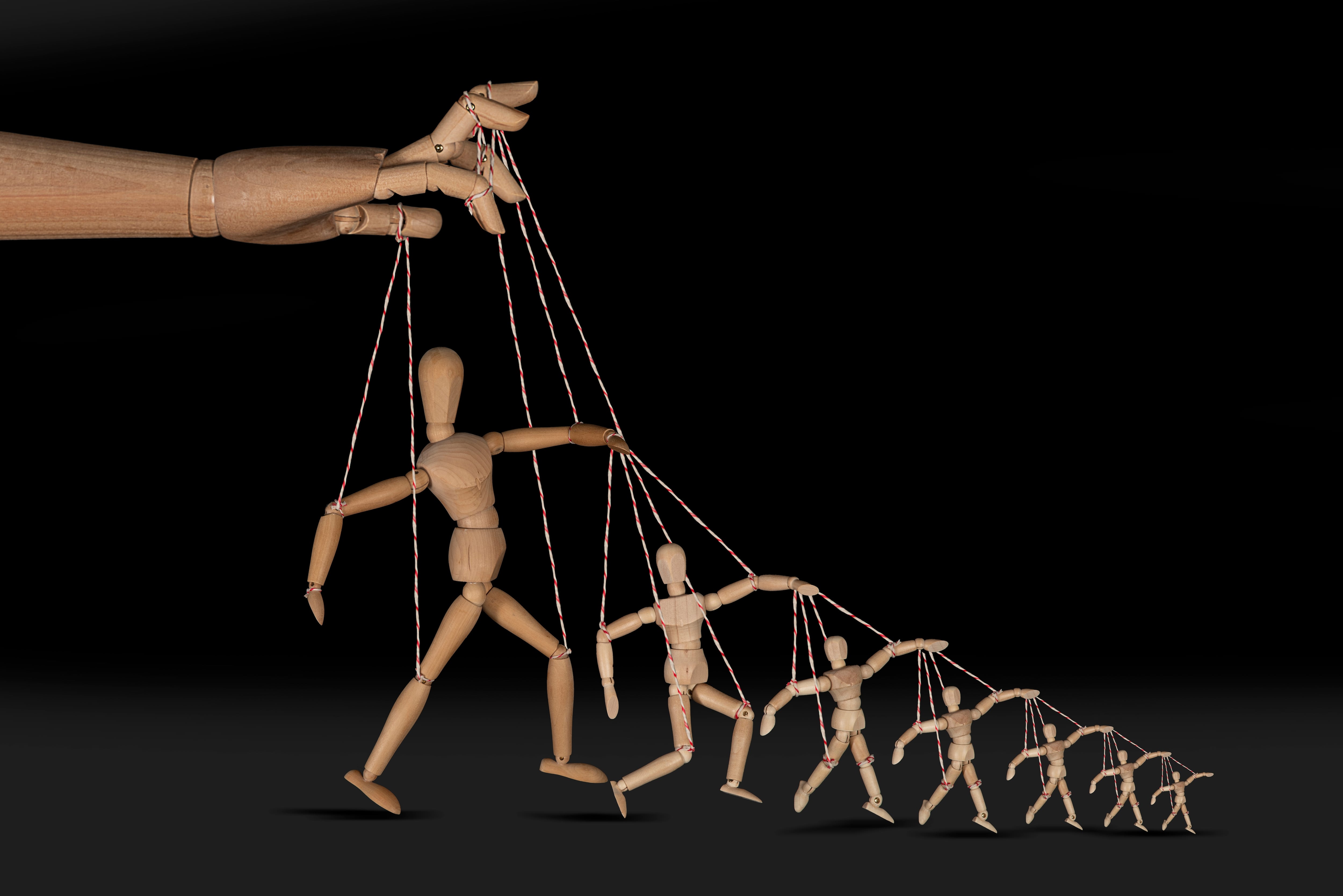 Populismo, mesianismo, dictadura, autocracia, líderes populistas. Mano maneja a figuras humanas como si fueran marionetas