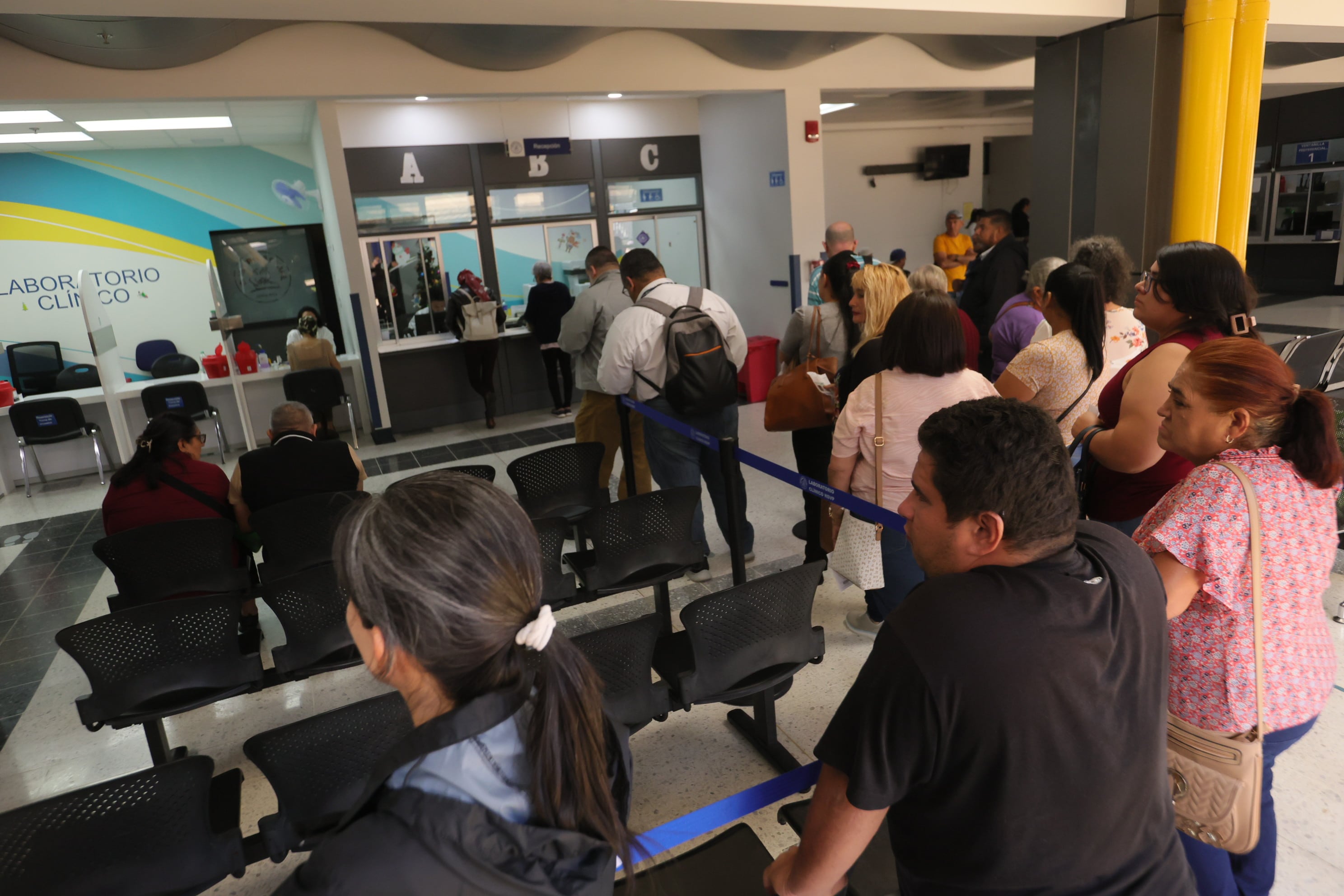 Varios pacientes esperan en fila y sentados en sillas ser atendidos en servicio de laboratorio y radiología, en hospital de Heredia.
