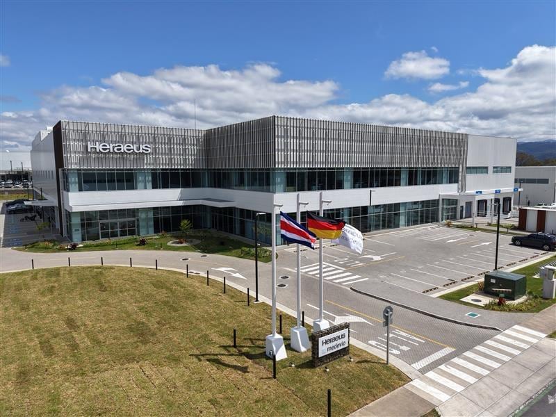 Vista exterior de la planta de Heraeus Medevio en la Zona Franca La Lima, Cartago, Costa Rica. En la imagen se observan las banderas de Costa Rica, Alemania y la empresa, junto con el edificio de modernas instalaciones.