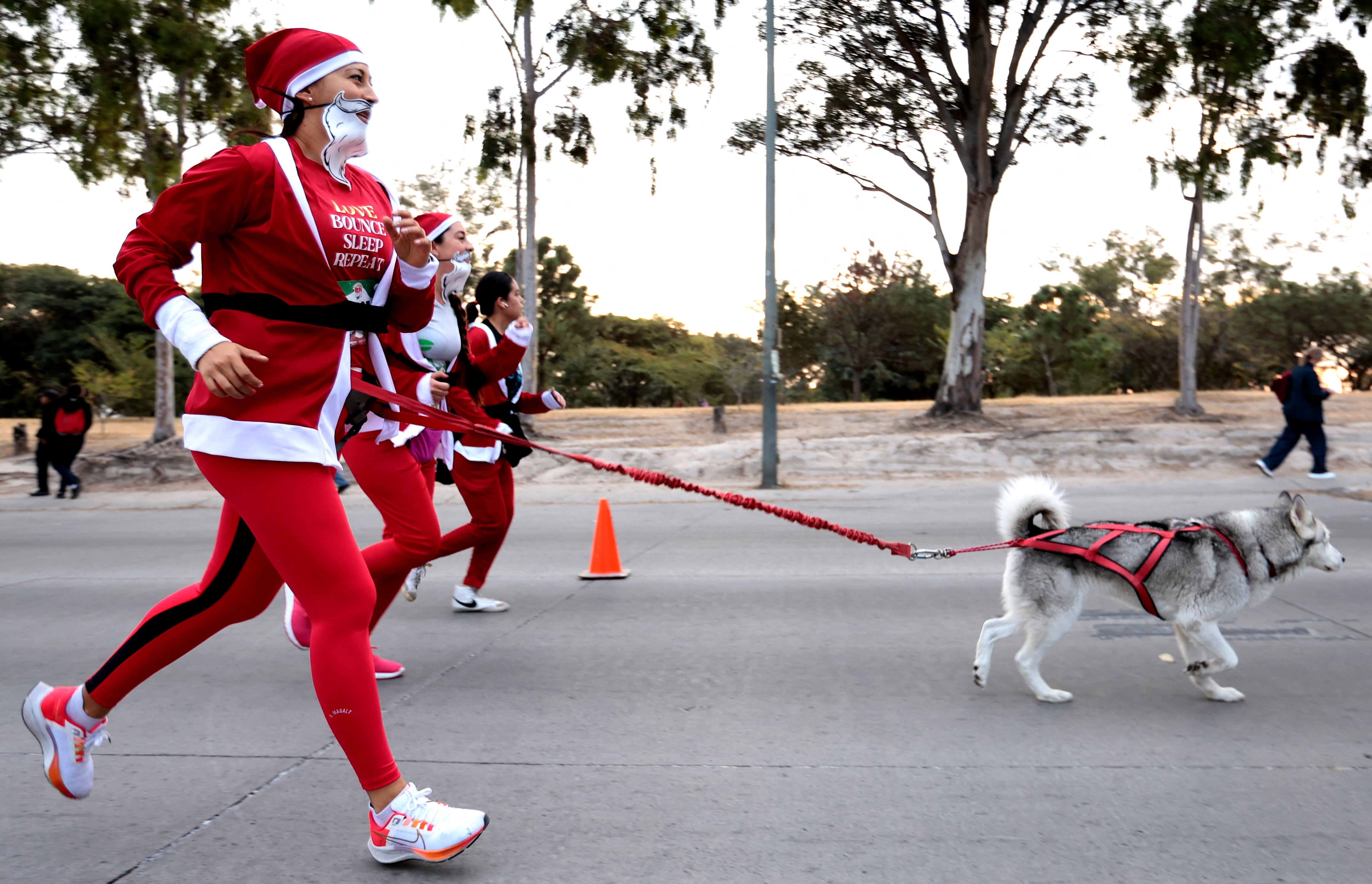 Corredoras vestidas como Santa Claus acompañadas de perros participan en la carrera 'Run Santa Run' en Zapopan, México, el 8 de diciembre de 2024.