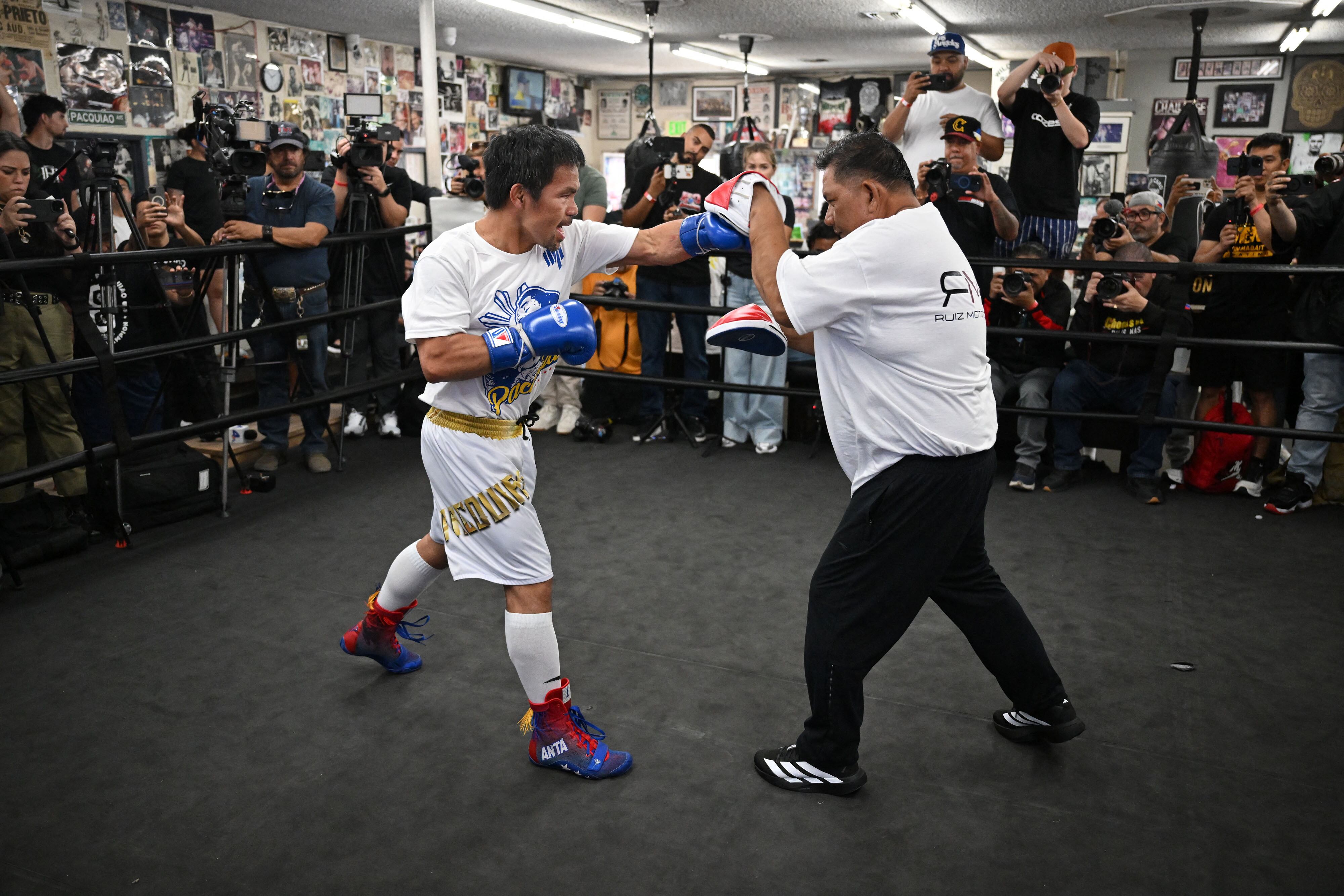 El boxeador filipino Manny "Pacman" Pacquiao (izq.) entrena con uno de sus entrenadores durante un entrenamiento de prensa en el Wild Card Boxing Club de Los Ángeles