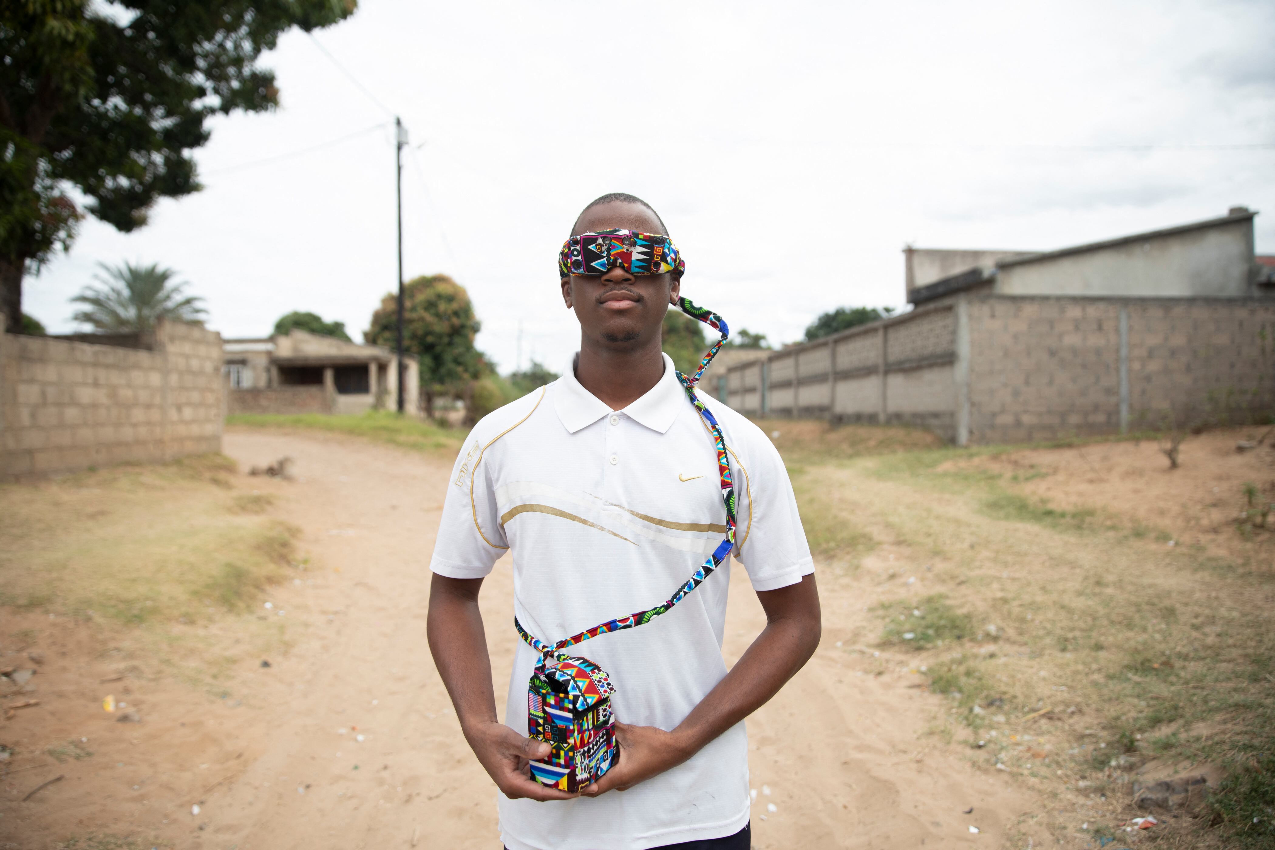 El estudiante de robótica e inventor Joao Antonio Rego (24) posa para un retrato con un prototipo de gafas inteligentes en su casa en Matola, el 14 de junio de 2025. Este prototipo es el más reciente de una serie desarrollada desde que Rego lanzó su proyecto Vision Hope en 2021, con el que ganó el premio Young Creative Award de Mozambique por innovación tecnológica al año siguiente. El dispositivo, similar a una máscara de realidad virtual, está equipado con sensores que detectan obstáculos; las vibraciones aumentan en intensidad conforme el objeto se acerca.
Entre las nuevas funciones destacan un mayor campo de detección de 120 grados y sensores más precisos, explicó Rego, estudiante de robótica e ingeniería electrónica en la Universidad Eduardo Mondlane.
(Foto: Amilton Neves / AFP)