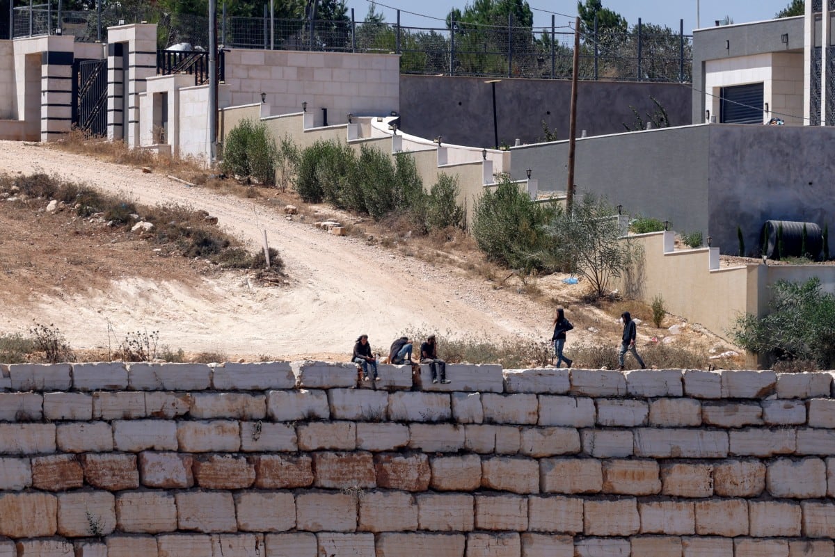 Colonos israelíes se congregan frente a viviendas palestinas en el poblado de Qusra, al sur de Nablus, en la Cisjordania ocupada, el 13 de agosto de 2026.