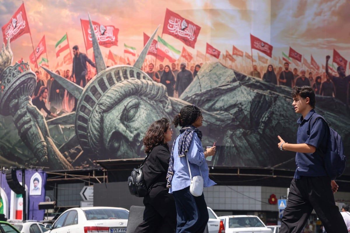 Personas caminan frente a una valla publicitaria antiestadounidense en la plaza Enghelab, en el centro de Teherán, el 2 de septiembre de 2026. L