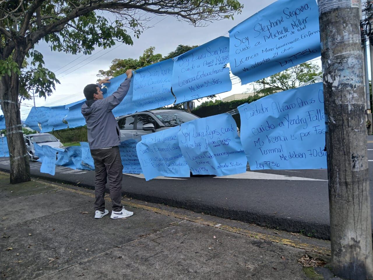 Un hombre, de espaldas, pone carteles con los mensajes de cuidadores.