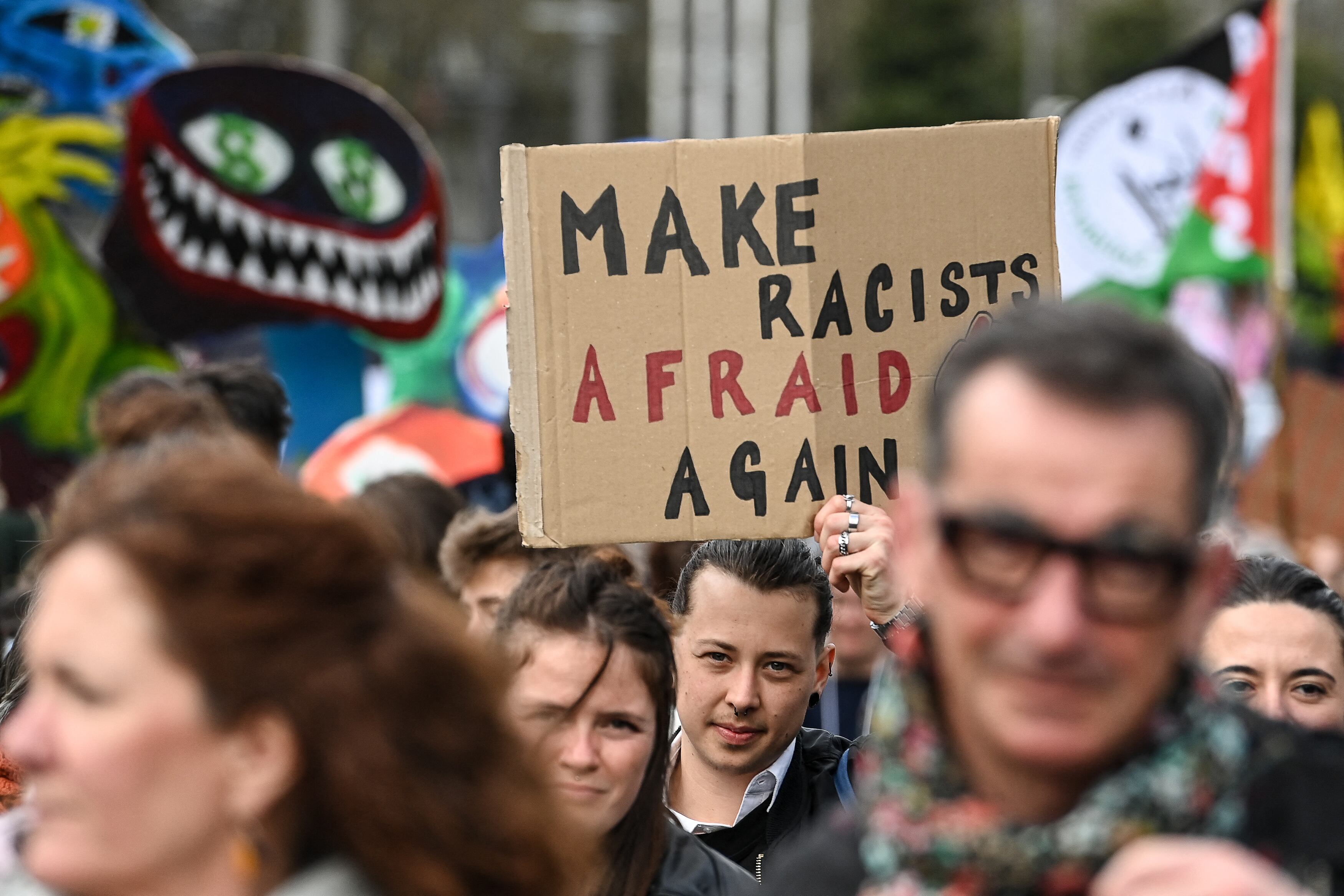 Un manifestante sostiene un cartel con la leyenda "Make racists afraid again" (Hacer que las racistas tengan miedo de nuevo), en referencia a la célebre frase de Donald Trump.