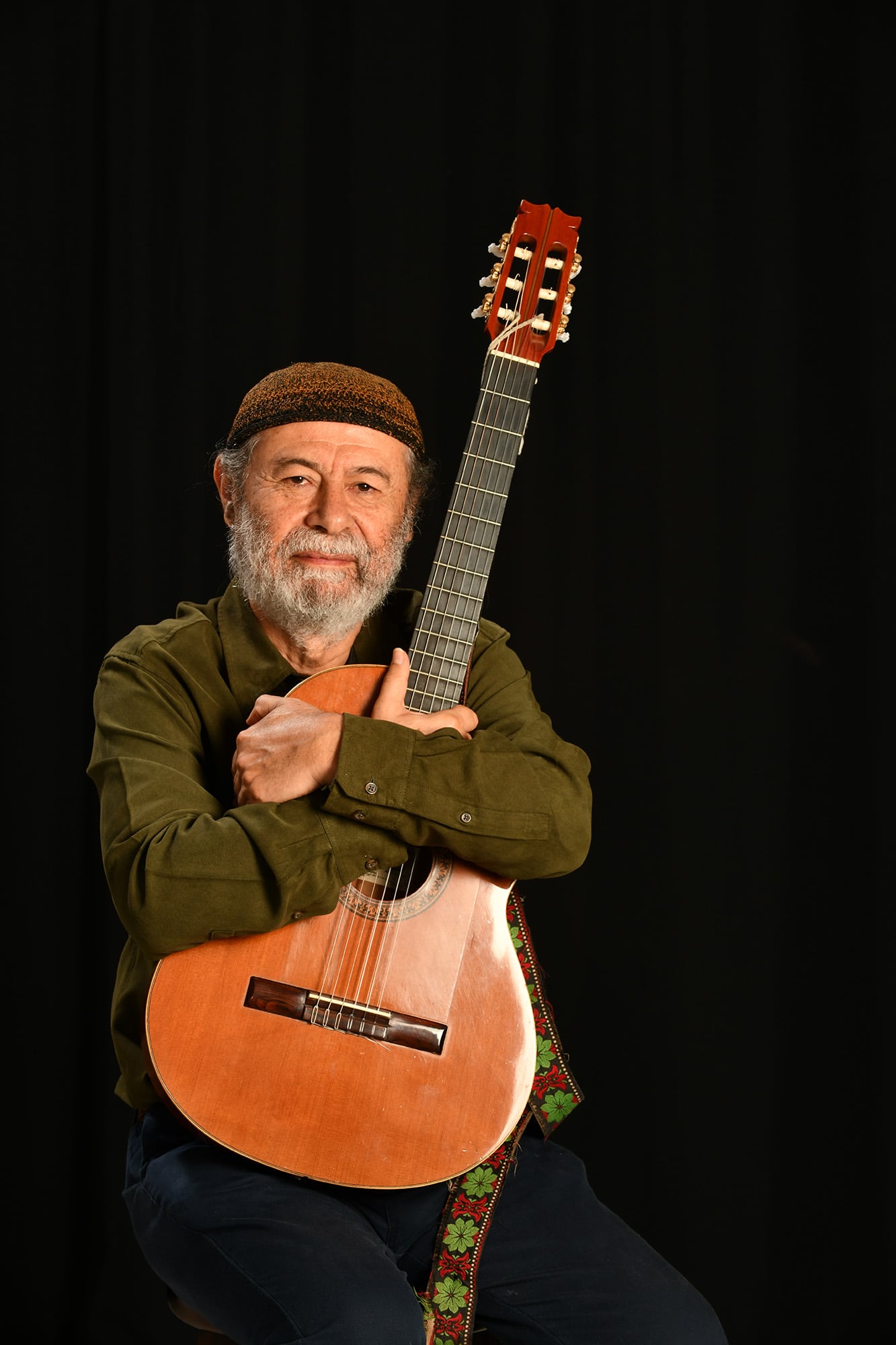 El músico Manuel Monestel posando de pie y sosteniendo su guitarra.