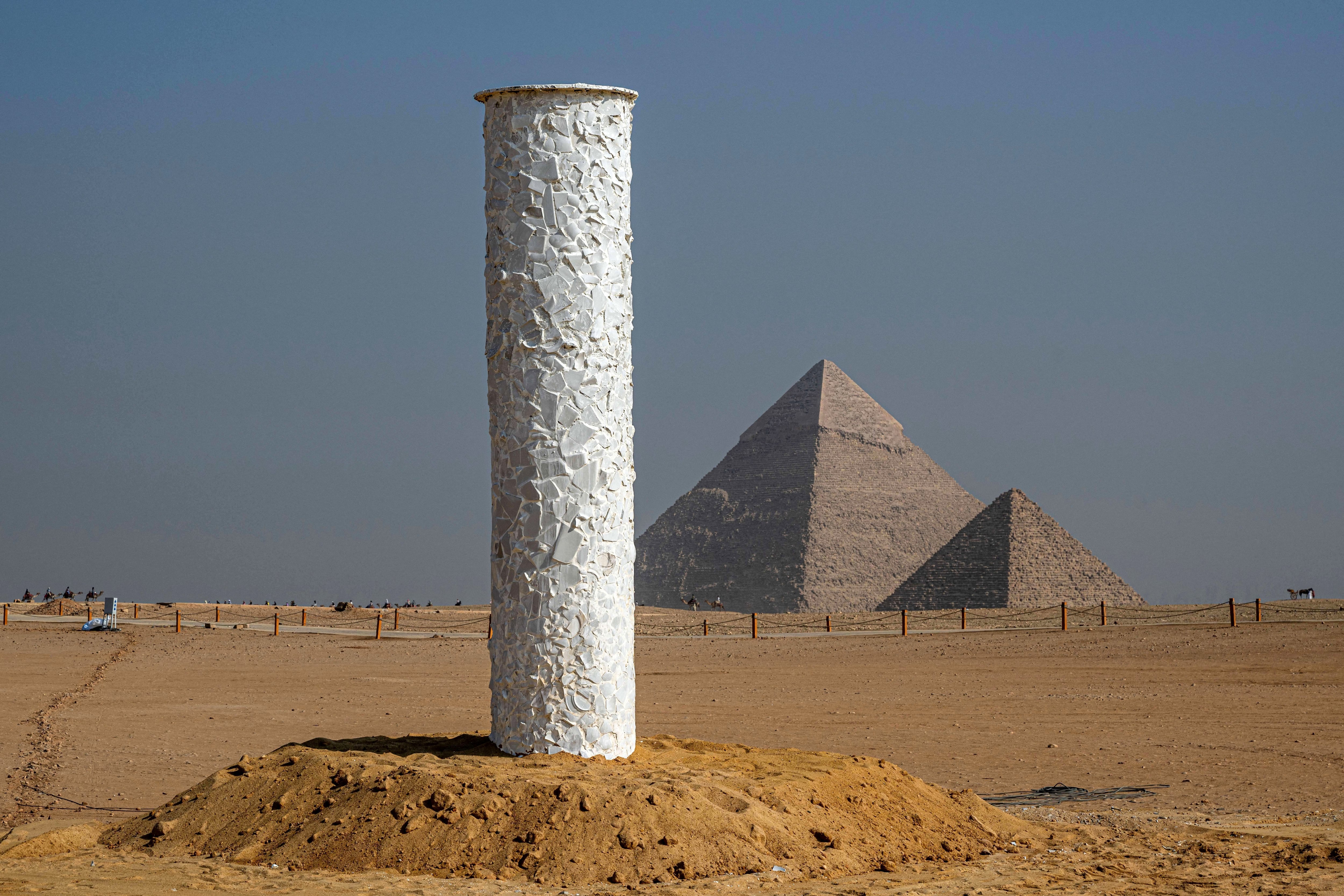 Vista de la instalación artística «Tótem Blanco de Luz» del artista King Houndekpinkou durante la quinta edición de la exposición de arte «Forever is Now» de Art d'Egypte en la necrópolis de las pirámides de Giza el 11 de noviembre de 2025.