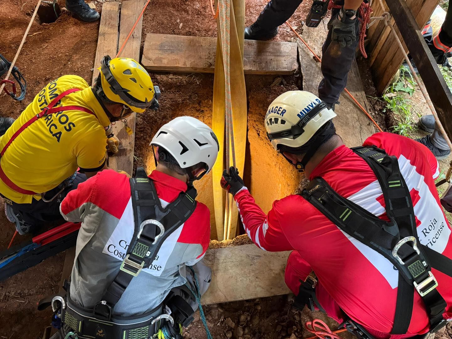 Un grupo de cruzrojistas y bomberos con poleas listos para bajar a un precipicio.