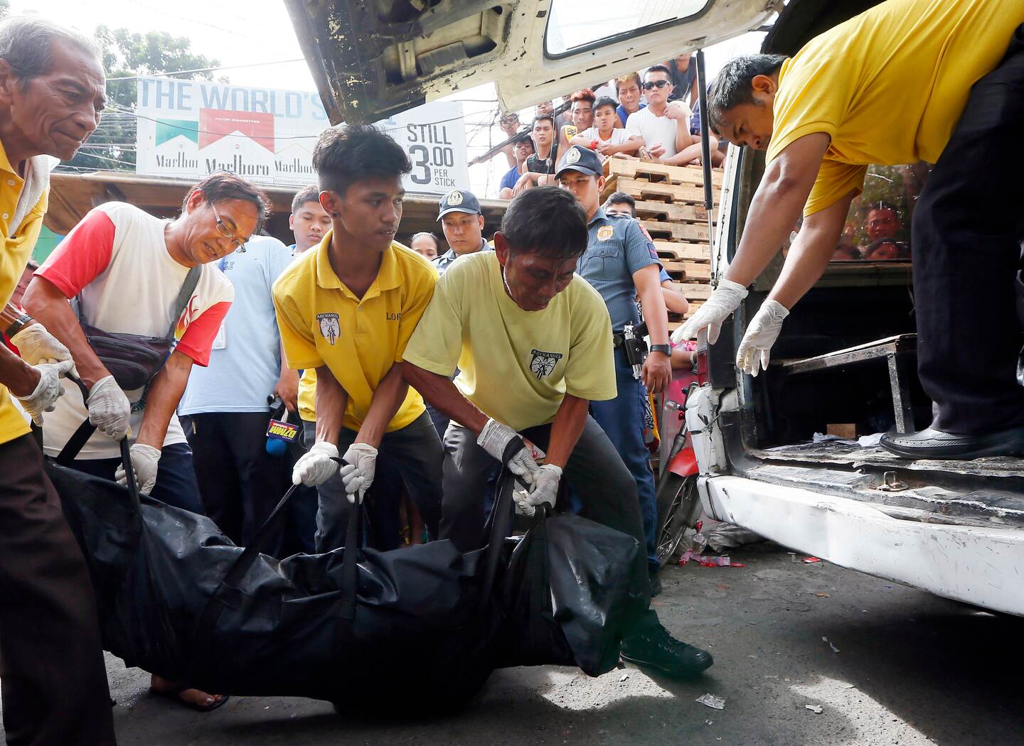 Residentes observan cómo los trabajadores cargan a una de cinco personas asesinadas en una presunta operación antidrogas de la policía en Manila, Filipinas, en noviembre del 2016.