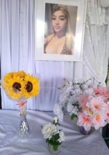 Se observa la foto de una joven es una especie de altar y ramos de flores en una mesa