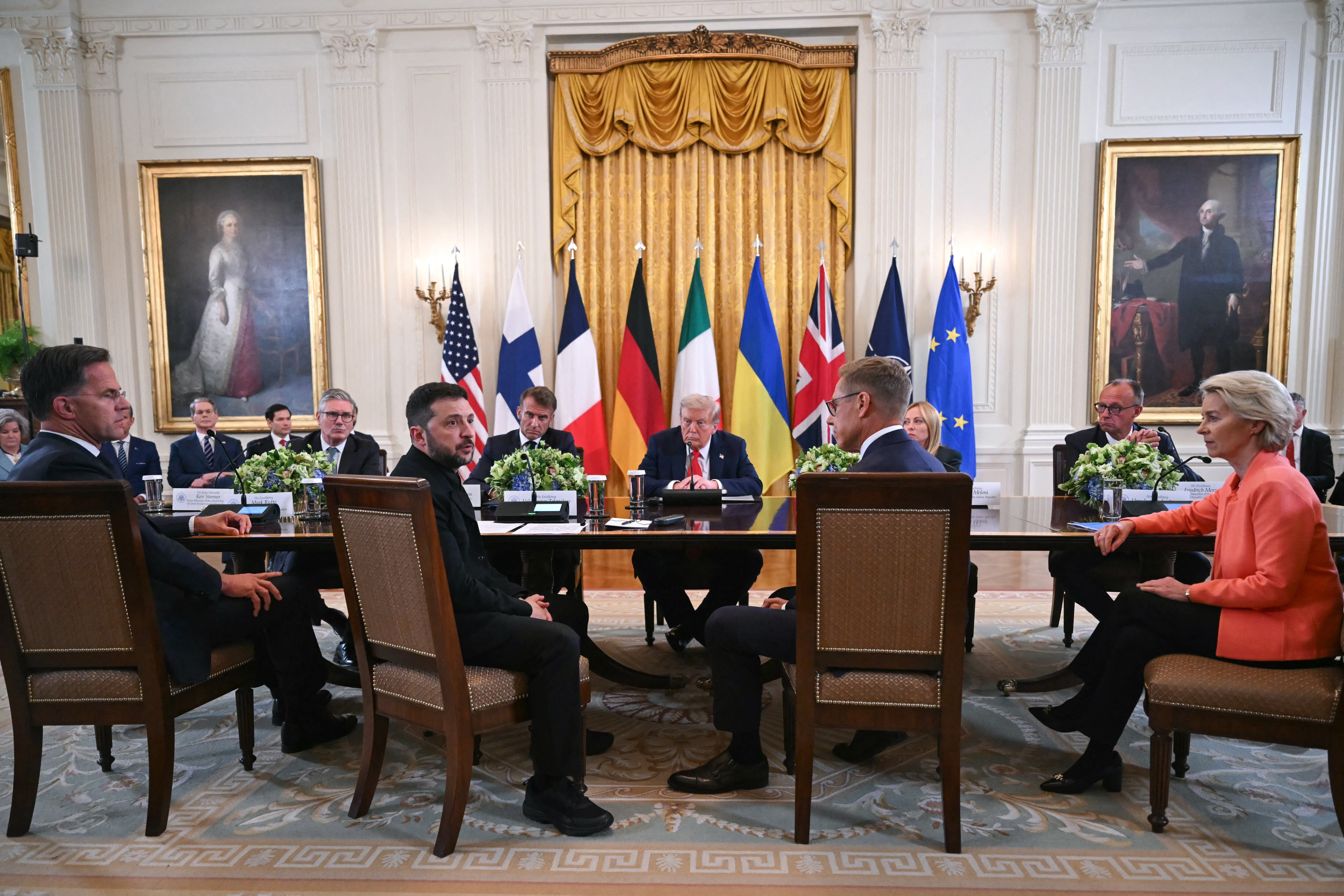 (L/R) NATO Secretary-General Mark Rutte, British Prime Minister Keir Starmer, Ukrainian President Volodymyr Zelensky, French President Emmanuel Macron, US President Donald Trump, Finnish President Alexander Stubb, Italian Prime Minister Giorgia Meloni, German Chancellor Friedrich Merz, and European Commission President Ursula von der Leyen participate in a meeting in the East Room of the White House in Washington, DC, on August 18, 2025. European leaders join Ukrainian President Volodymyr Zelensky in talks with US President Donald Trump on August 18, as they try to find a way to end Russia's offensive. The leaders heading to Washington on Monday to appear alongside Zelensky call themselves the "coalition of the willing." (Photo by ANDREW CABALLERO-REYNOLDS / AFP)