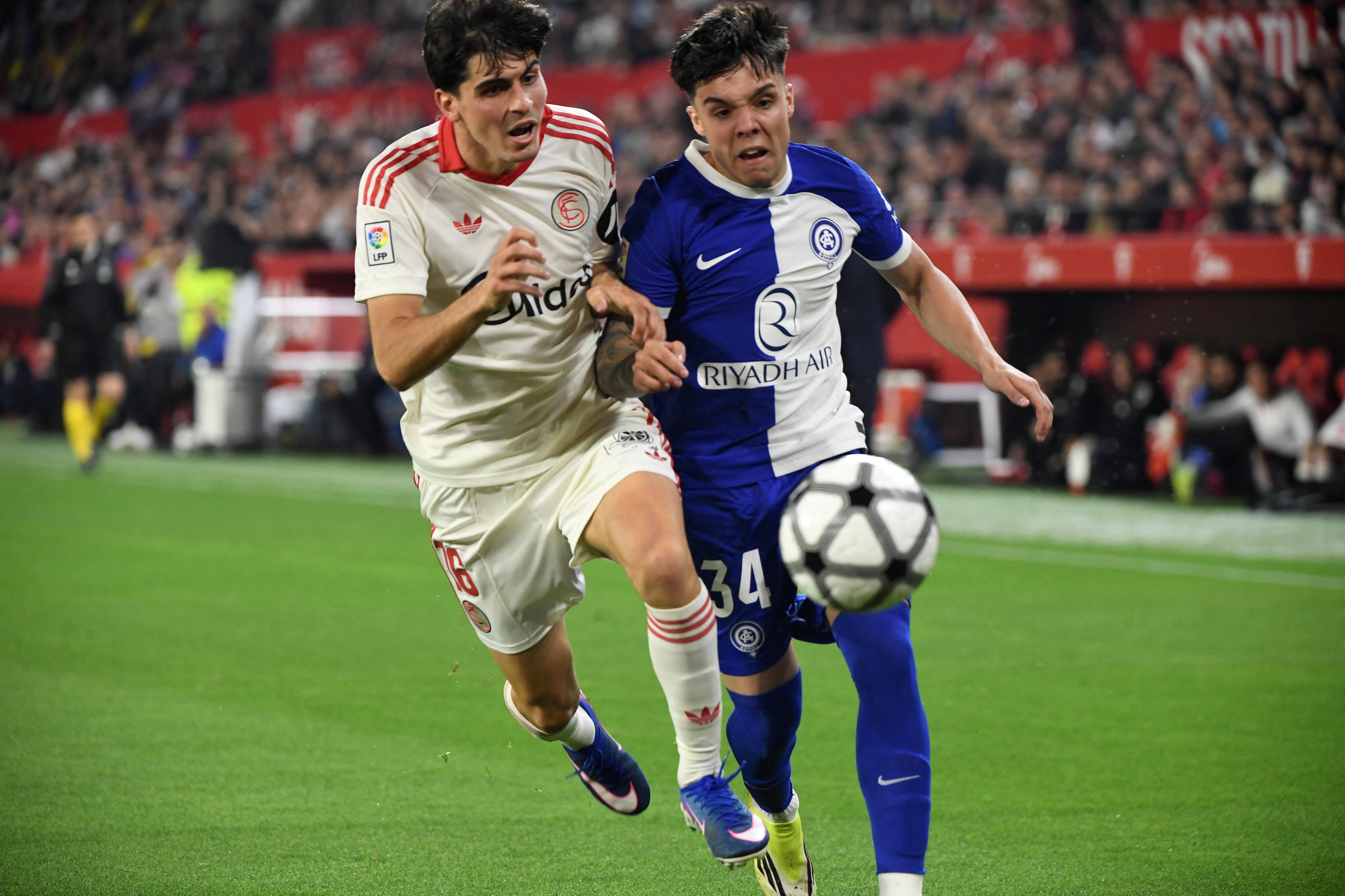 Juanlu Sánchea, del Sevilla, disputa el balón con Julio Romo, del Atletico de Madrid, en el esttadio Ramón Sánchez Pizjuán por la Liga Española.