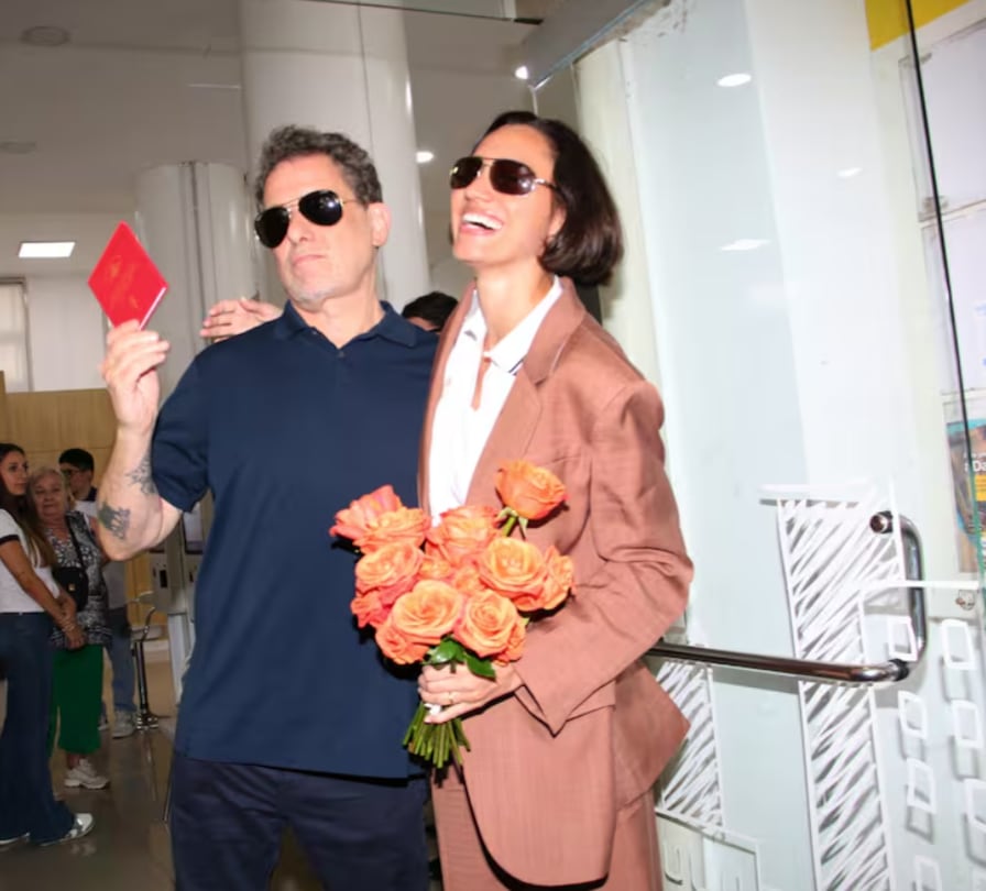 Andrés Calamaro junto a su ahora esposa Natalí Franco el día de su matrimonio. Él lleva camisa negra y lentes oscuros, ella un traje color terracota con blusa blanca.