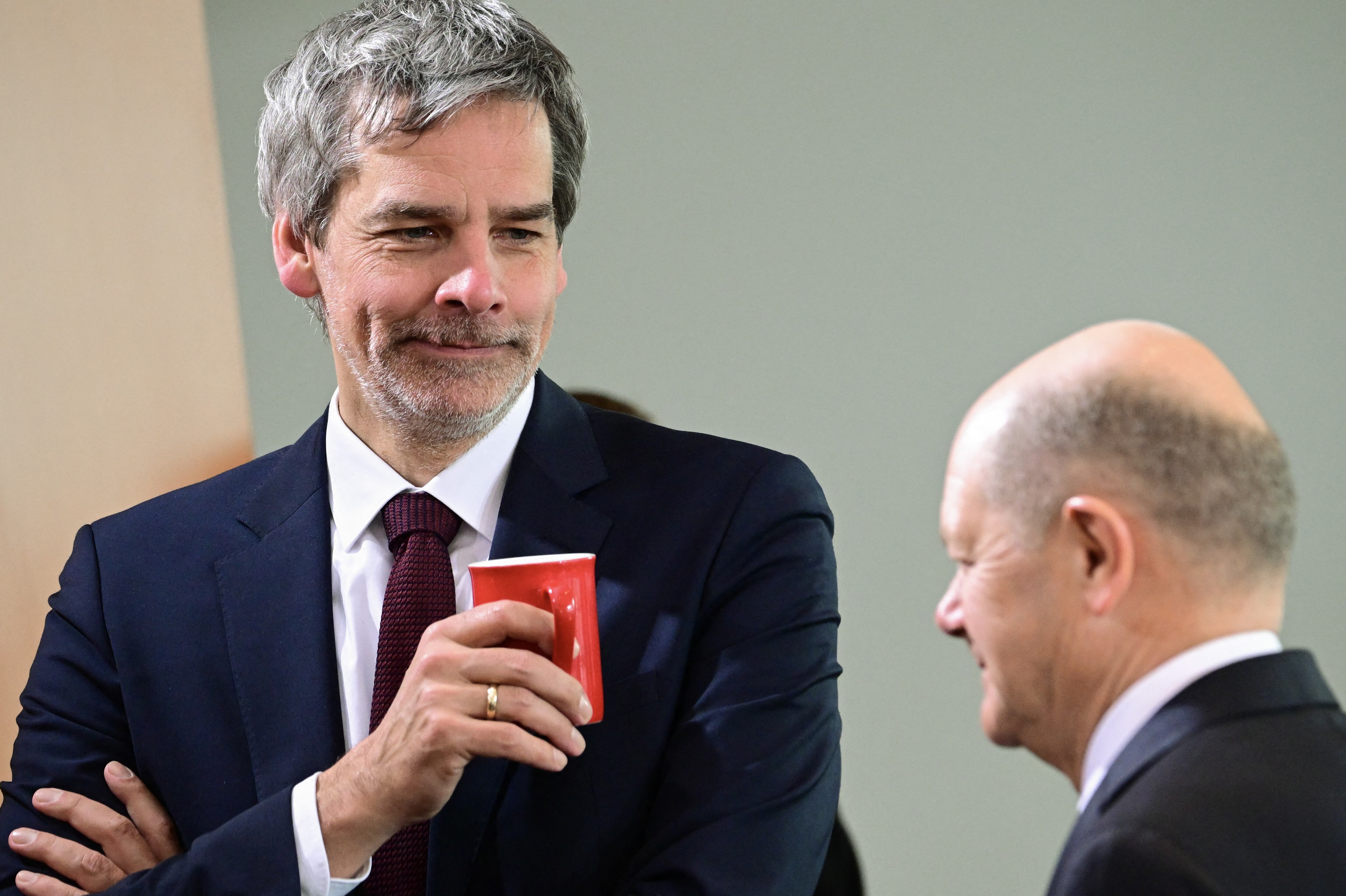 the German Government's spokesman Steffen Hebestreit holds a mug and talks with German Chancellor Olaf Scholz at the start of a cabinet meeting at the Chancellery in Berlin on March 12, 2025. (Photo by Tobias SCHWARZ / AFP)