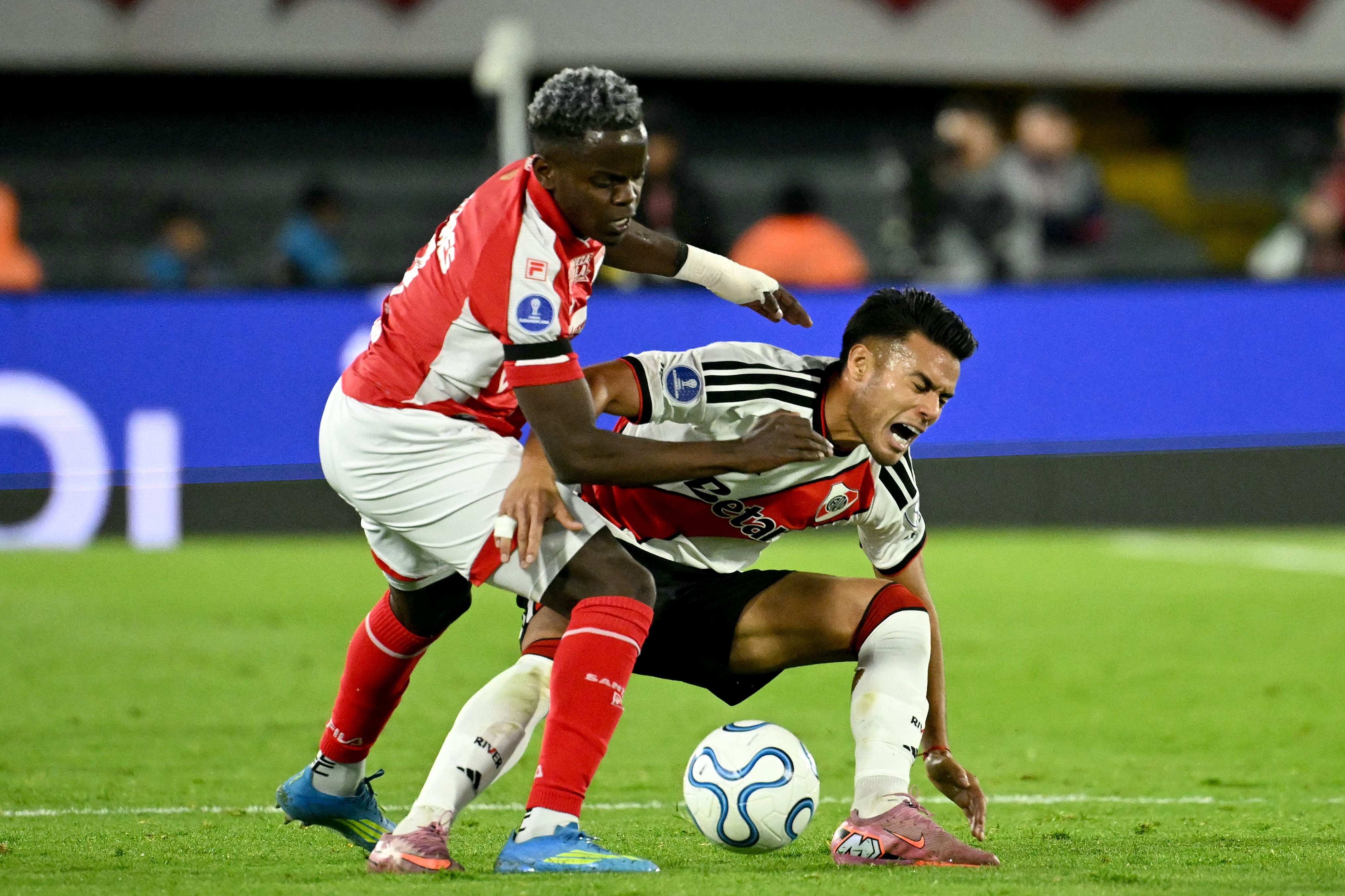El volante de Independiente de Santa Fe Jhojan Torres (izq.) disputa el balón con Fausto Vera, del River Plate, durante el partido por la Copa Sudamericana en el estadio Nemesio Camacho 'El Campín' de Bogotá.