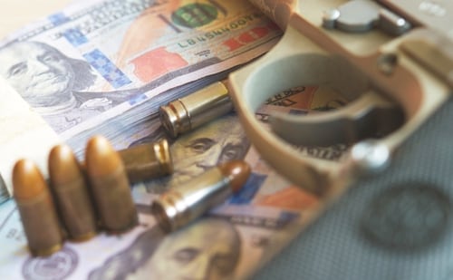 Primer plano de municiones y billetes de dólares, representando la influencia del crimen organizado en la corrupción y la economía.