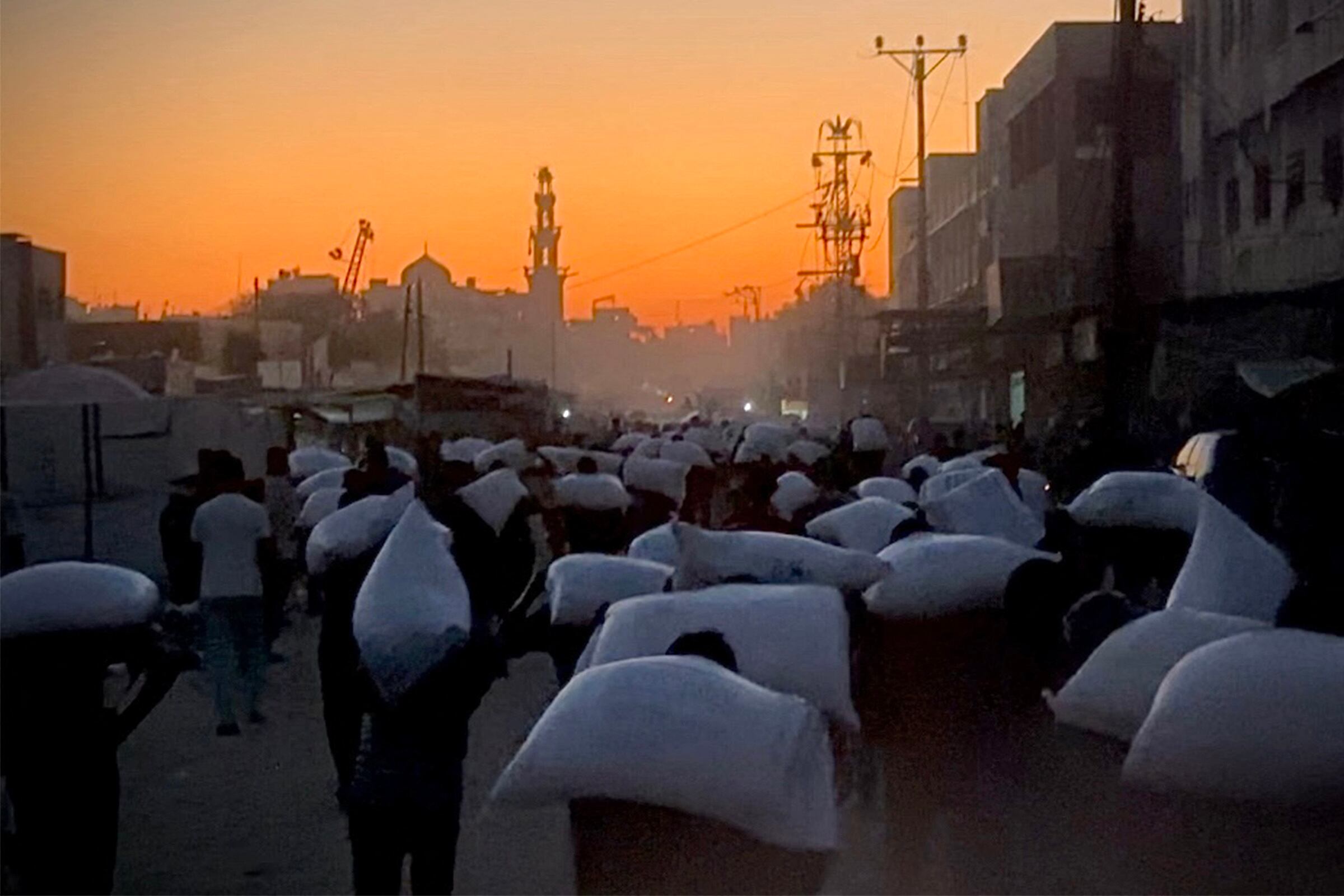 Hombres con sacos de harina robados de un camión que transportaba alimentos en Khan Yunis, al sur de la Franja de Gaza, este 22 de julio. Fotografía: