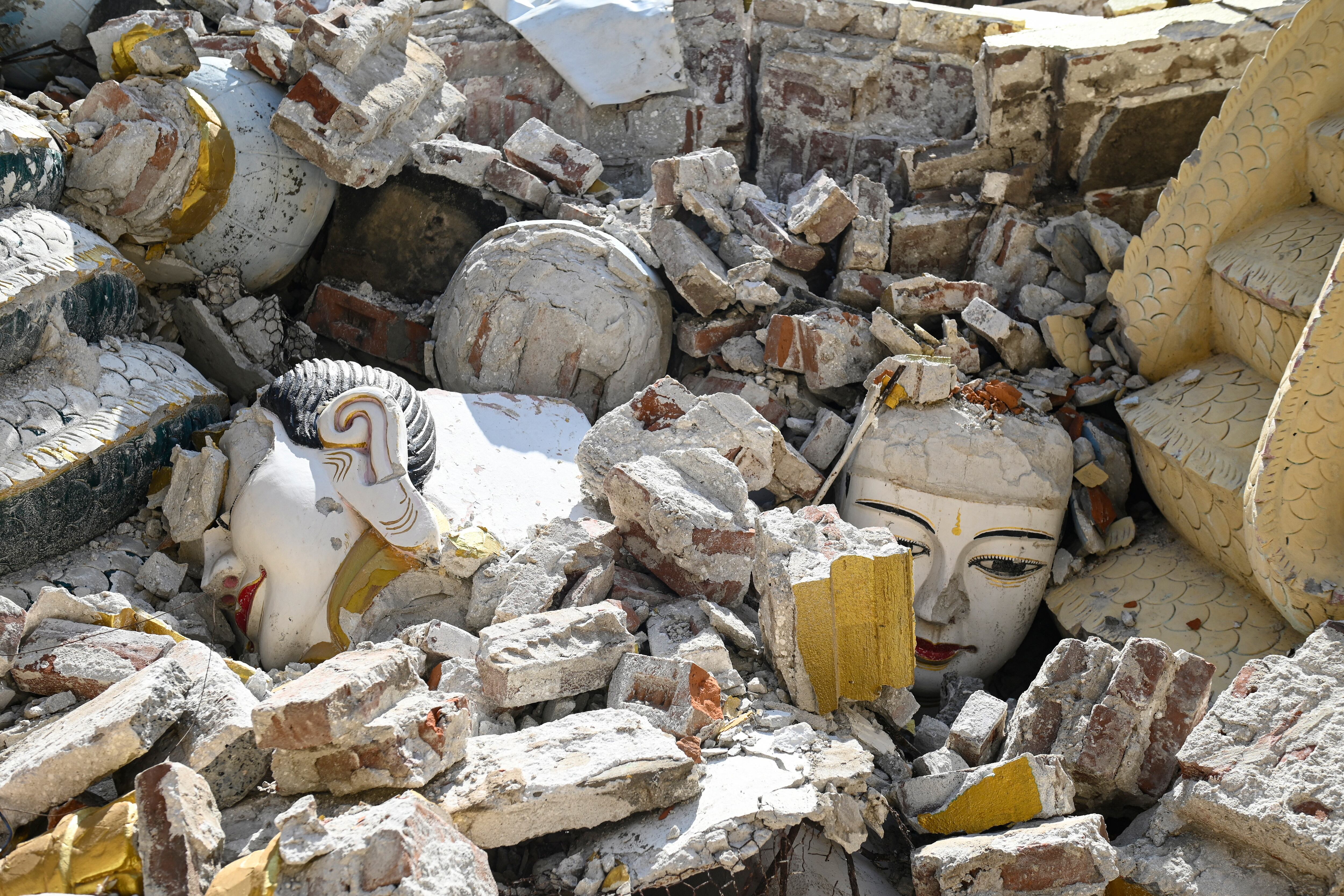 PRIMER PLANO - Esta foto tomada el 12 de abril de 2025 muestra estatuas de Buda dañadas, rodeadas por los escombros de un edificio colapsado en Mandalay, tras el devastador terremoto del 28 de marzo. Cuando un fuerte sismo sacudió Myanmar el mes pasado, siglos de historia sagrada se vinieron abajo: imponentes ídolos de Buda, estupas altísimas y la pagoda completamente blanca donde Khin Sein, de 83 años, ha rezado durante la mayor parte de su vida.