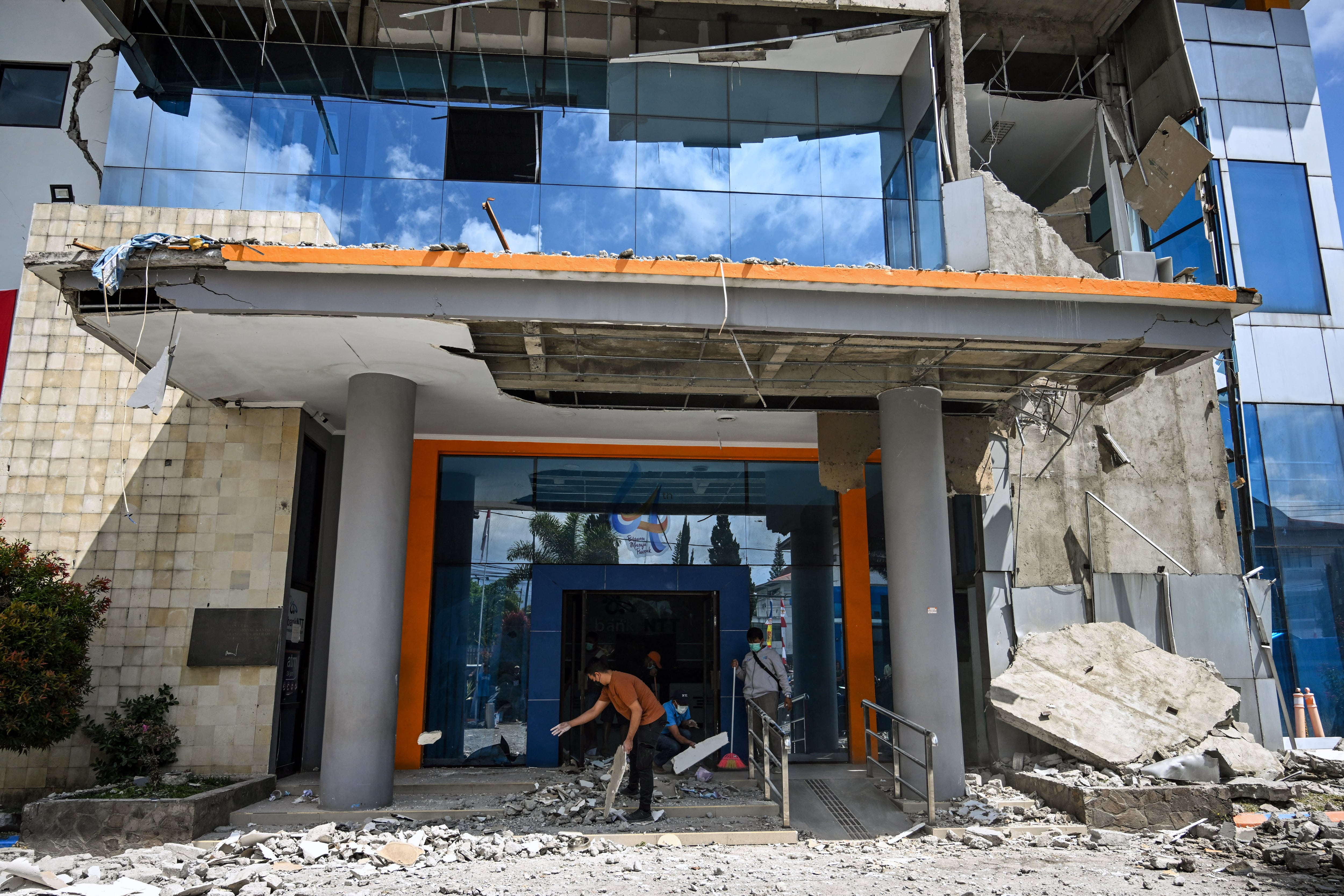 en la imagen un empleado limpia los escombros a las afueras de un edificio en Indonesia tras el terremoto de 7,7