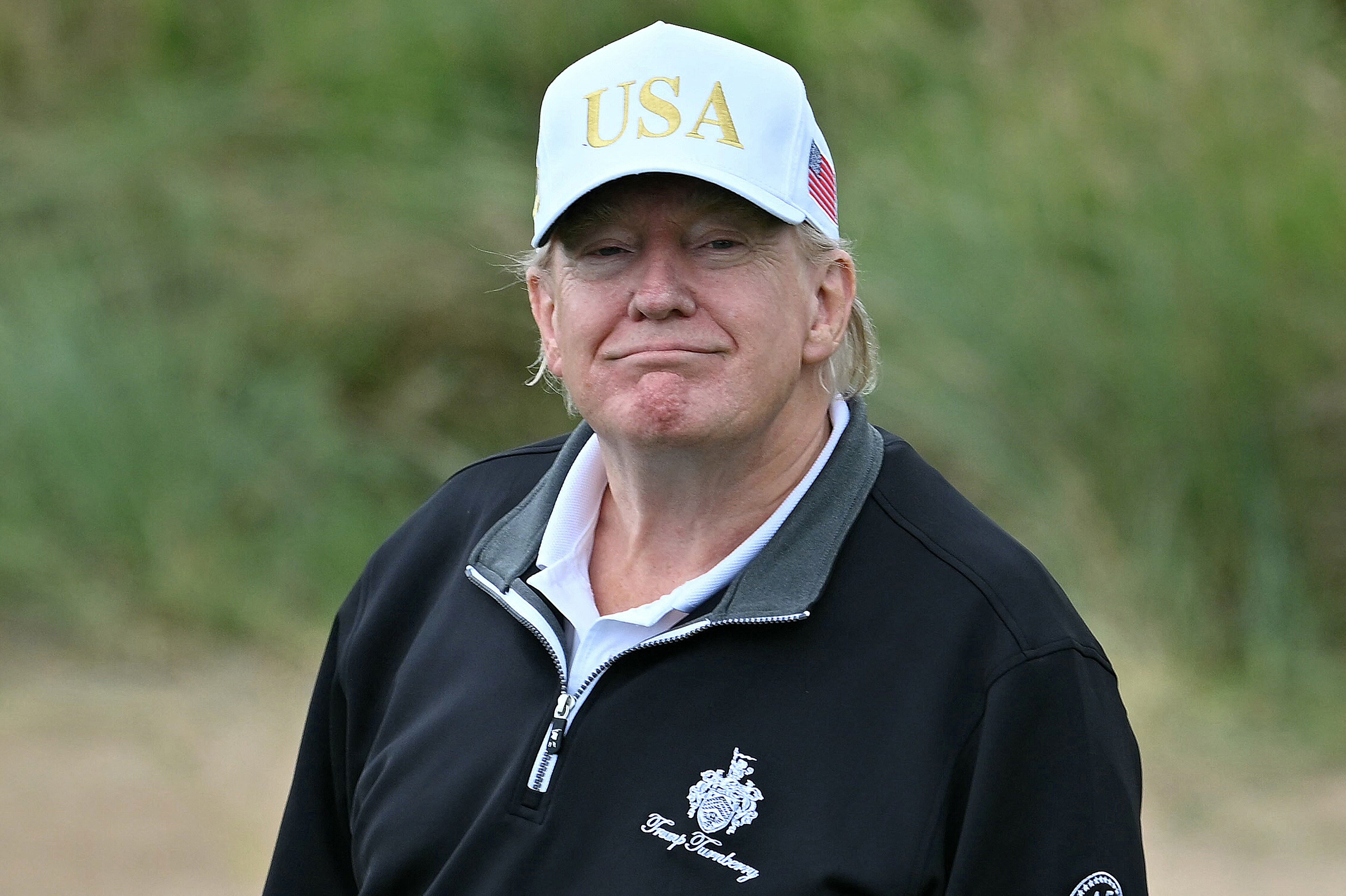 US President Donald Trump (C), flanked by his sons Eric Trump (R) and Donald Trump Jr. (L) cuts the ribbon on the first tee to officially open the Trump International Golf Links course in Balmedie, Aberdeenshire, north east Scotland on July 29, 2025. (Photo by Brendan Smialowski / AFP)