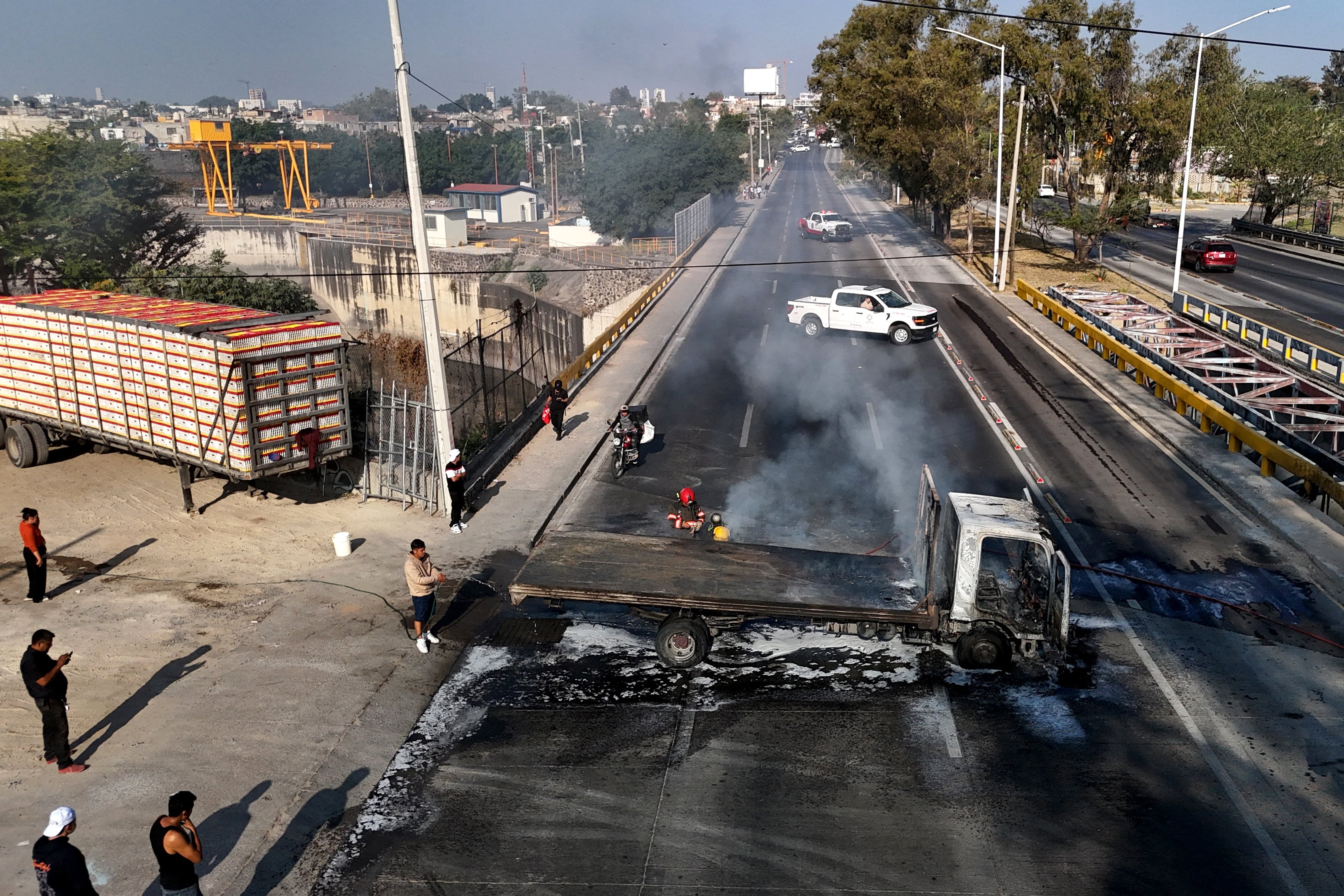 Un hombre apaga un camión en llamas incendiado por grupos del crimen organizado en respuesta a un operativo en Jalisco para detener a un objetivo prioritario de seguridad, en una de las principales avenidas de Zapopan, estado de Jalisco, México, el 22 de febrero de 2026.
Civiles armados bloquearon varias carreteras en el estado de Jalisco, en el oeste de México, tras un operativo de fuerzas federales en la localidad de Tapalpa, informaron autoridades locales.
Jalisco, que albergará cuatro partidos del próximo Mundial 2026, es bastión del poderoso Cártel Jalisco Nueva Generación (CJNG) y ha sido escenario de varios episodios de violencia en los últimos años. (Foto de Ulises RUIZ / AFP)