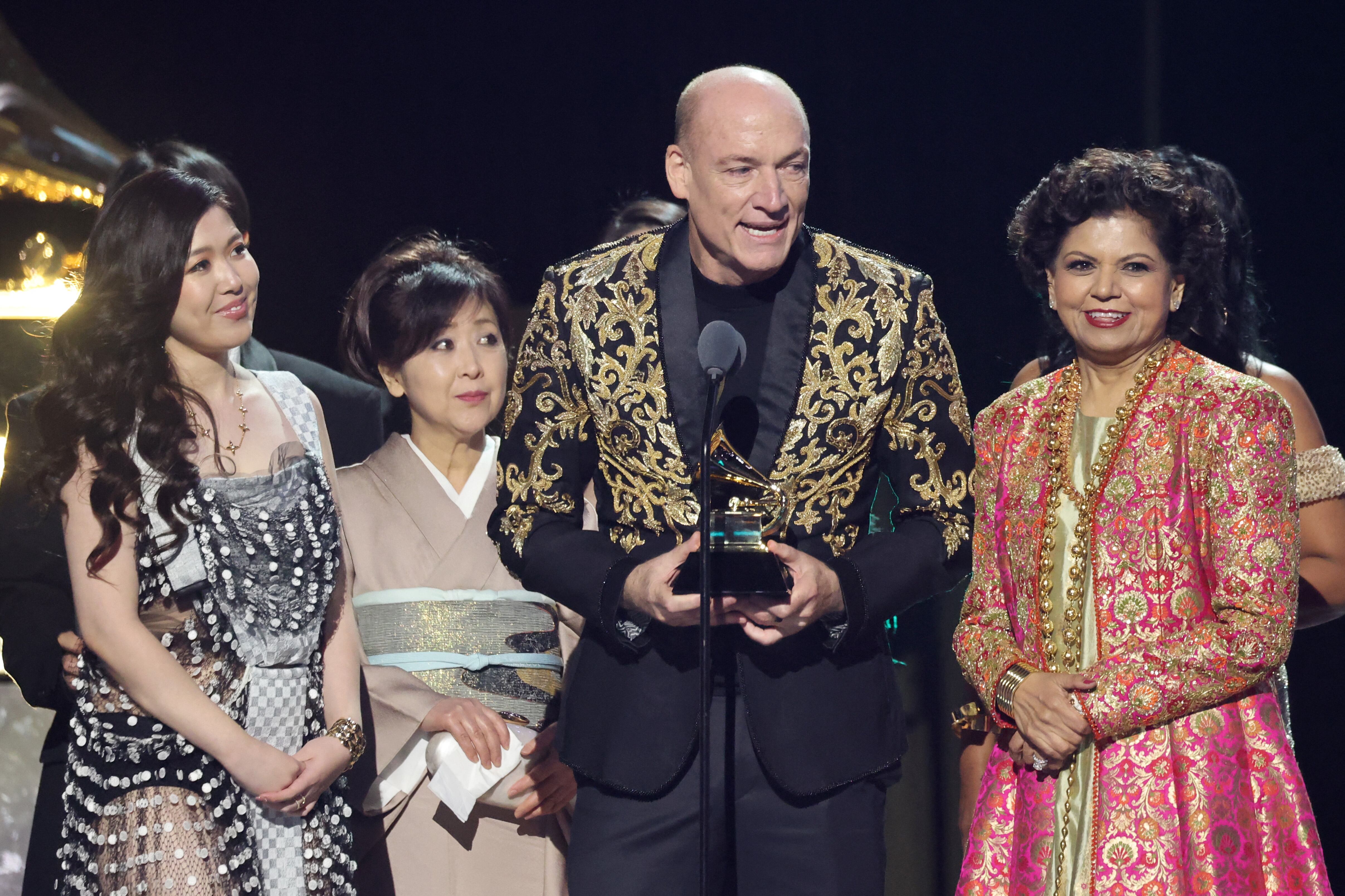 Artistas reciben premio vestidos con trajes de colores brillantes