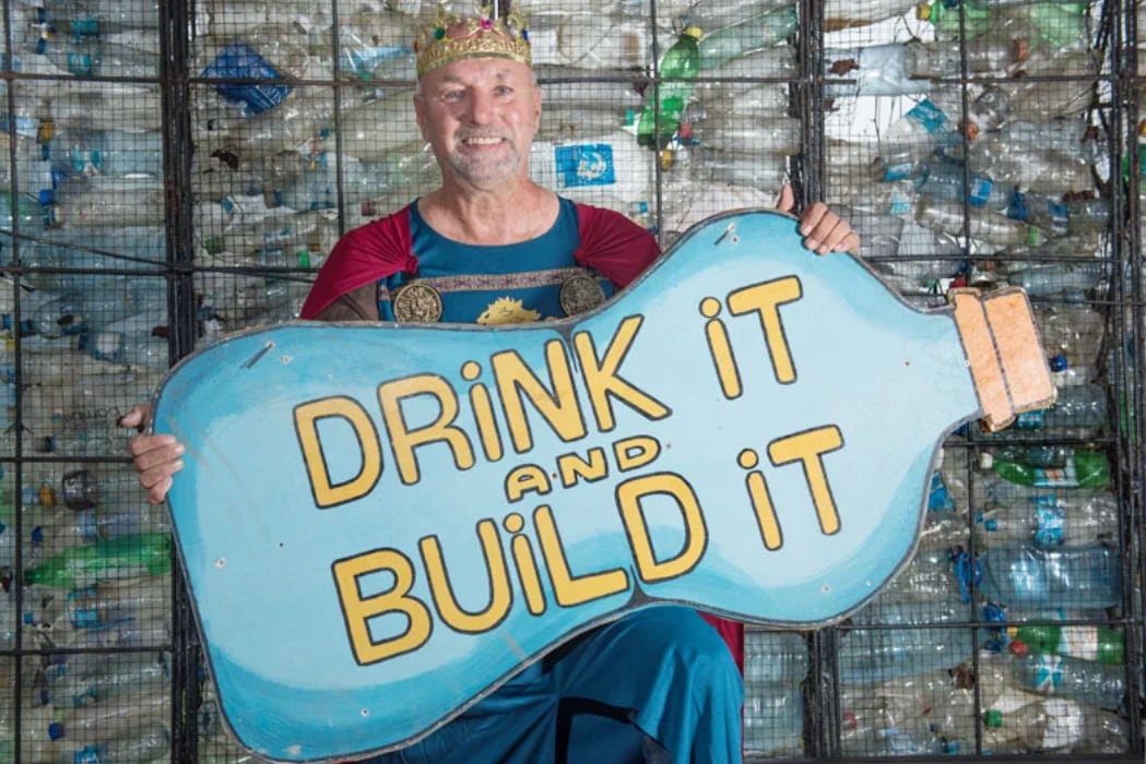 El canadiense Robert Bezeau, creador de Plastic Bottle Village, viste un disfraz temático mientras presenta el castillo construido con miles de botellas de plástico recicladas.