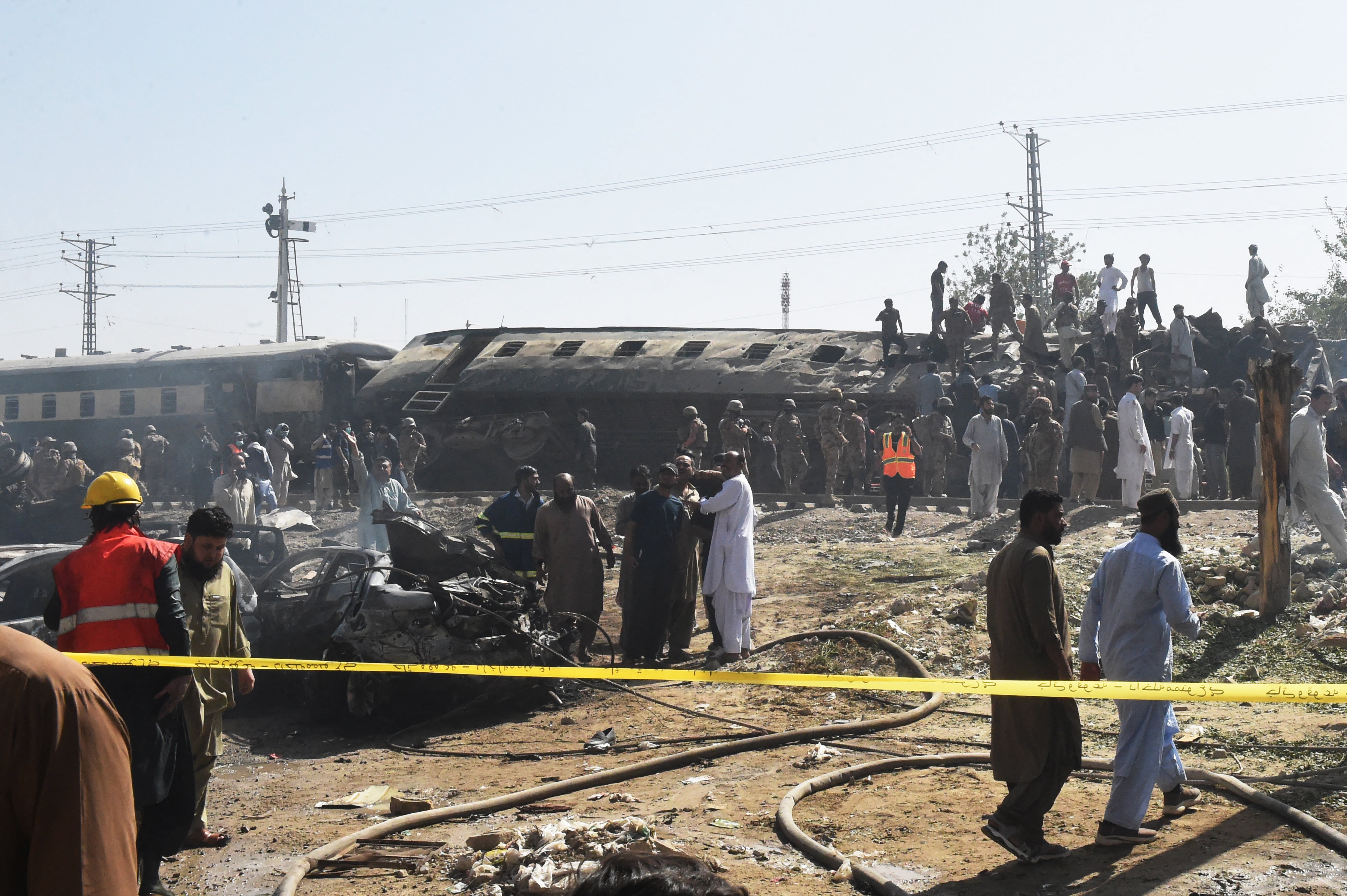 en la imagen, Personal de seguridad inspecciona vagones descarrilados y dañados después de que una explosión tuvo como objetivo un tren en Quetta el 24 de mayo de 2026