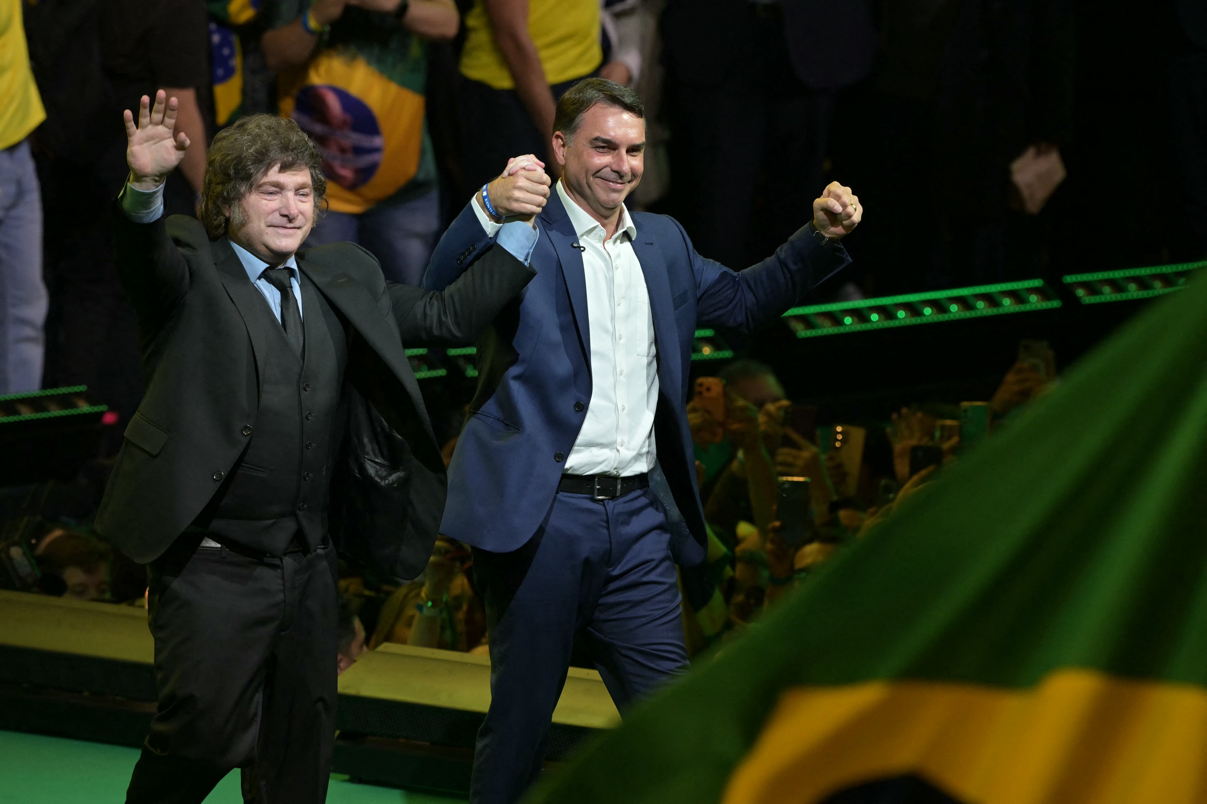 Argentina's President Javier Milei and Brazil's right-wing presidential hopeful Flavio Bolsonaro wave during the launching of the latter's candidacy within the Liberal Party convention, in Sao Paulo, Brazil on July 25, 2026. Battered by a string of political crises, Flavio Bolsonaro launched his candidacy for Brazil's October presidential election, seeking to follow in the footsteps of his father, Jair Bolsonaro, who is serving house arrest for plotting a coup after losing the election in 2022. (Photo by Nelson ALMEIDA / AFP)