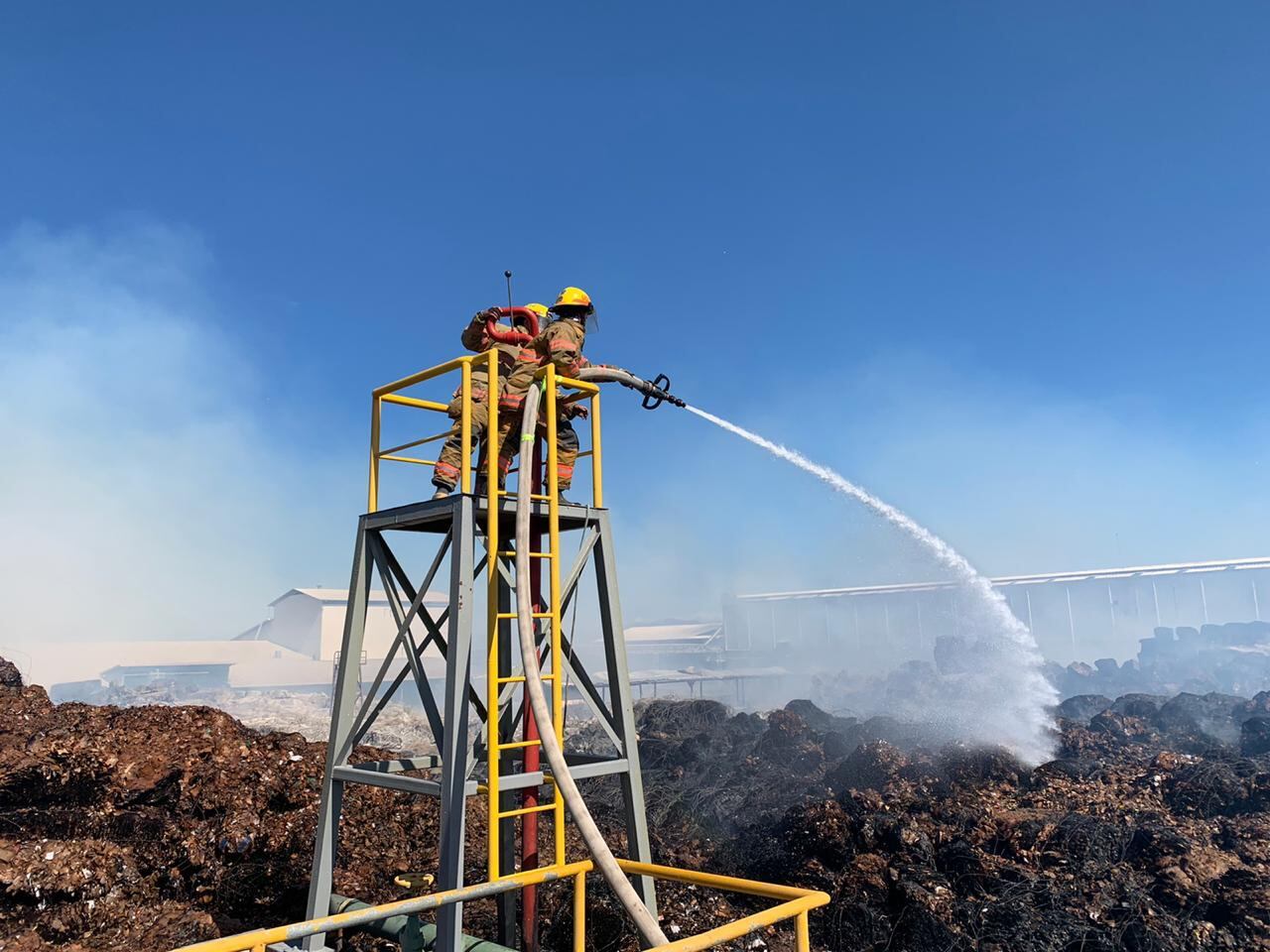 Sobre el material hirviente, los bomberos lanzaban agua este domingo, 24 horas después de que comenzó el fuego. Foto: Cortesía.