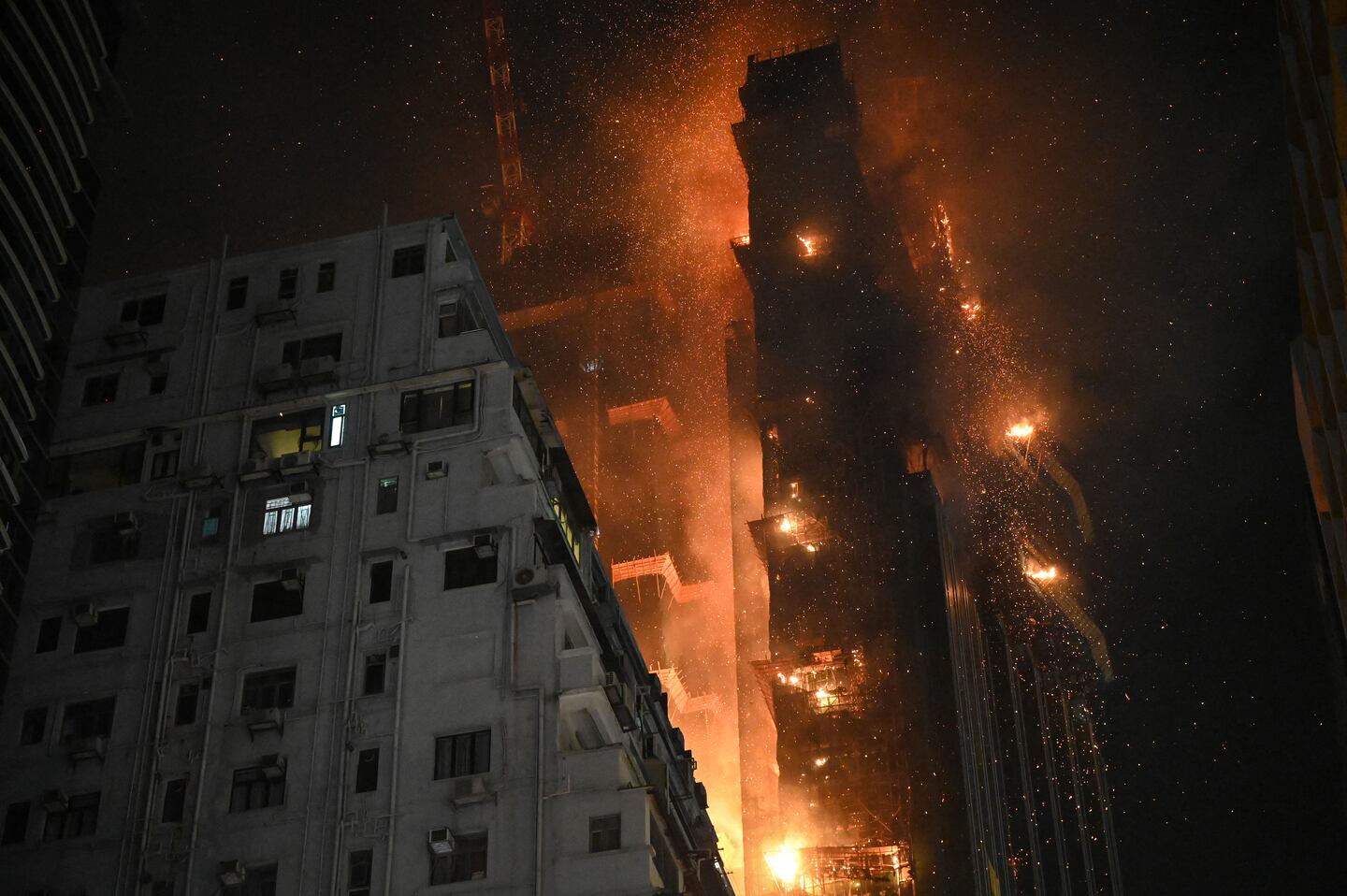 A high-rise building is engulfed in flames and smoke during a fire incident in Tai Po, with emergency response efforts supported by the Hong Kong Insurance Authority.