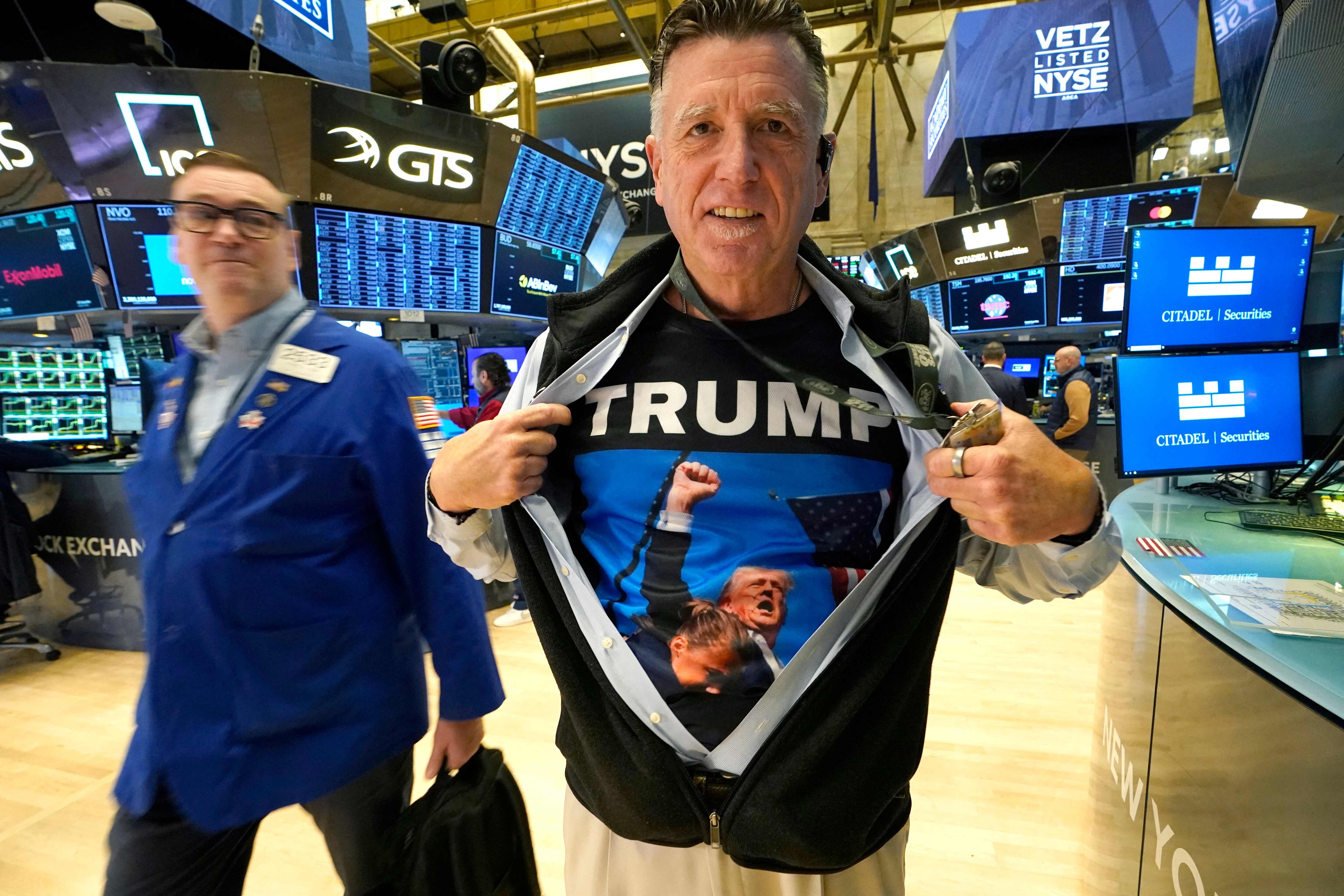 Trader Walter Lundon shows off his shirt featuring US President-elect Donald Trump, on the floor of the New York Stock Exchange (NYSE) in New York City on November 6, 2024. Wall Street stocks surged in opening trading on Wall Street Wednesday after US voters sent Donald Trump back to the White House and delivered him a Republican Senate. Major indices were up 1.8 percent or more in the early going as hopes about expected tax cuts and regulatory easing more than offset worries about higher tariffs. (Photo by TIMOTHY A. CLARY / AFP)