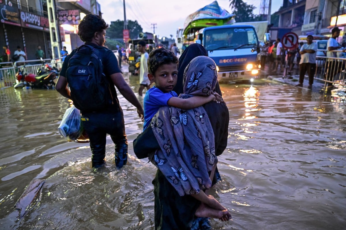 Una mujer lleva a un niño por las calles inundadas luego de una lluvia intensa en Wellampitiya en Sri Lanka.