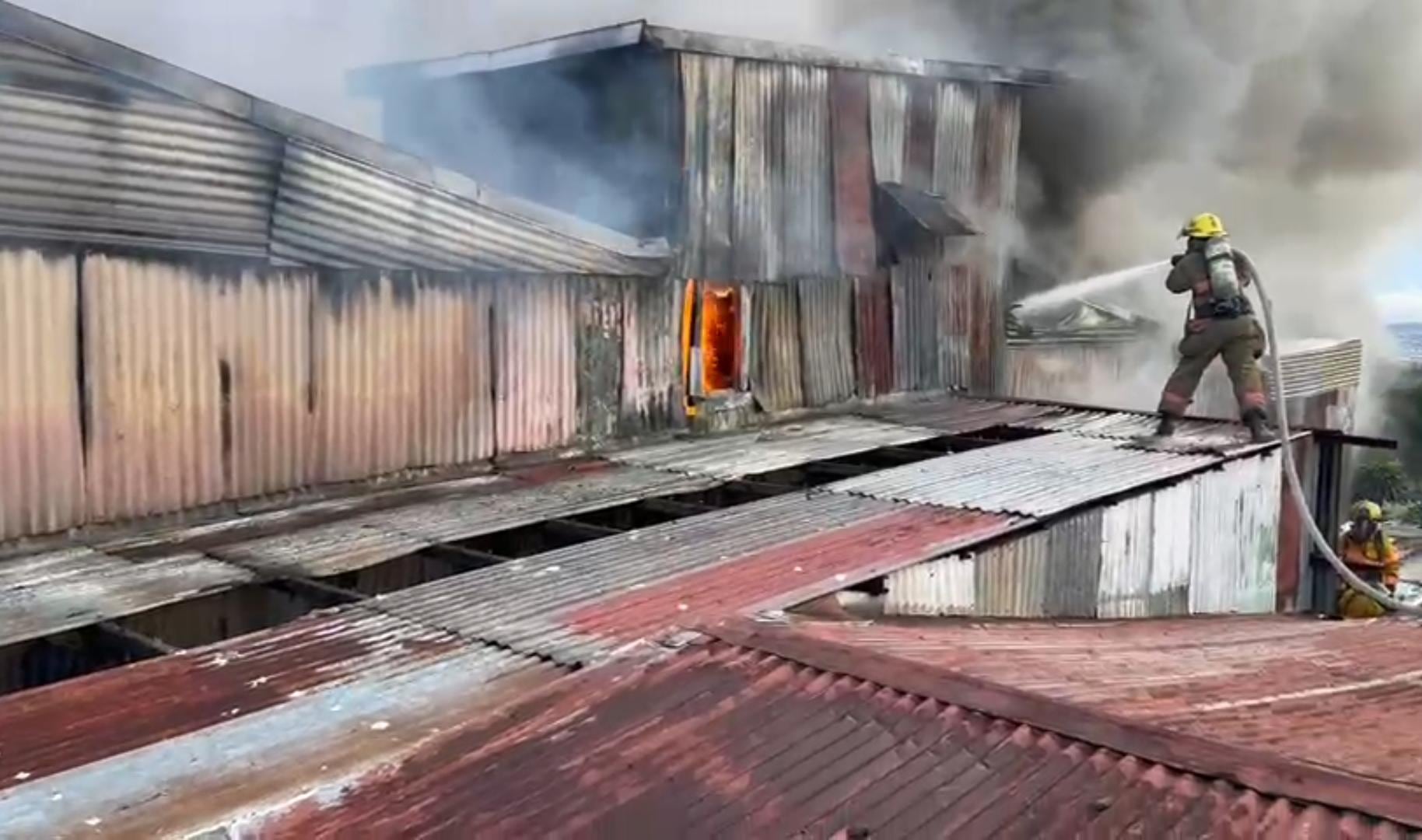 Un bombero apagando incendio en el techo de la vivienda.