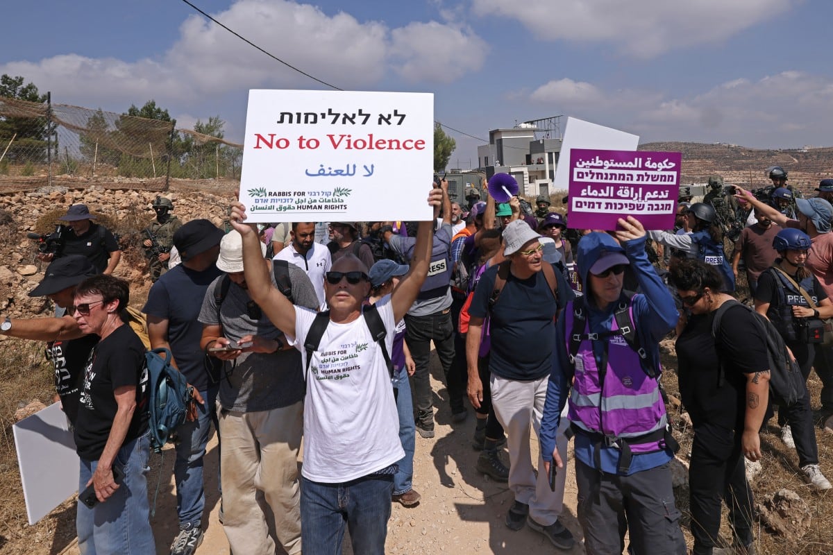 Activistas israelíes de izquierda y voluntarios de solidaridad se reúnen frente a una vivienda palestina sitiada por colonos israelíes en la localidad de Qusra, al sur de Nablus, en la Cisjordania ocupada, el 14 de agosto de 2026.