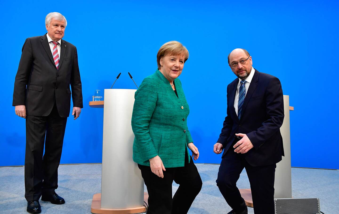 (L-R) Horst Seehofer, leader of the conservative Christian Social Union (CSU), German Chancellor Angela Merkel, leader of the conservative Christian Democratic Union (CDU), and Martin Schulz, leader of the social democratic SPD party, pose after giving a press conference in Berlin on February 7, 2018, after conservatives and the Social Democrats sealed a deal on a new coalition, potentially ending four months of political standstill in Europe's top economy. / AFP PHOTO / Tobias SCHWARZ
