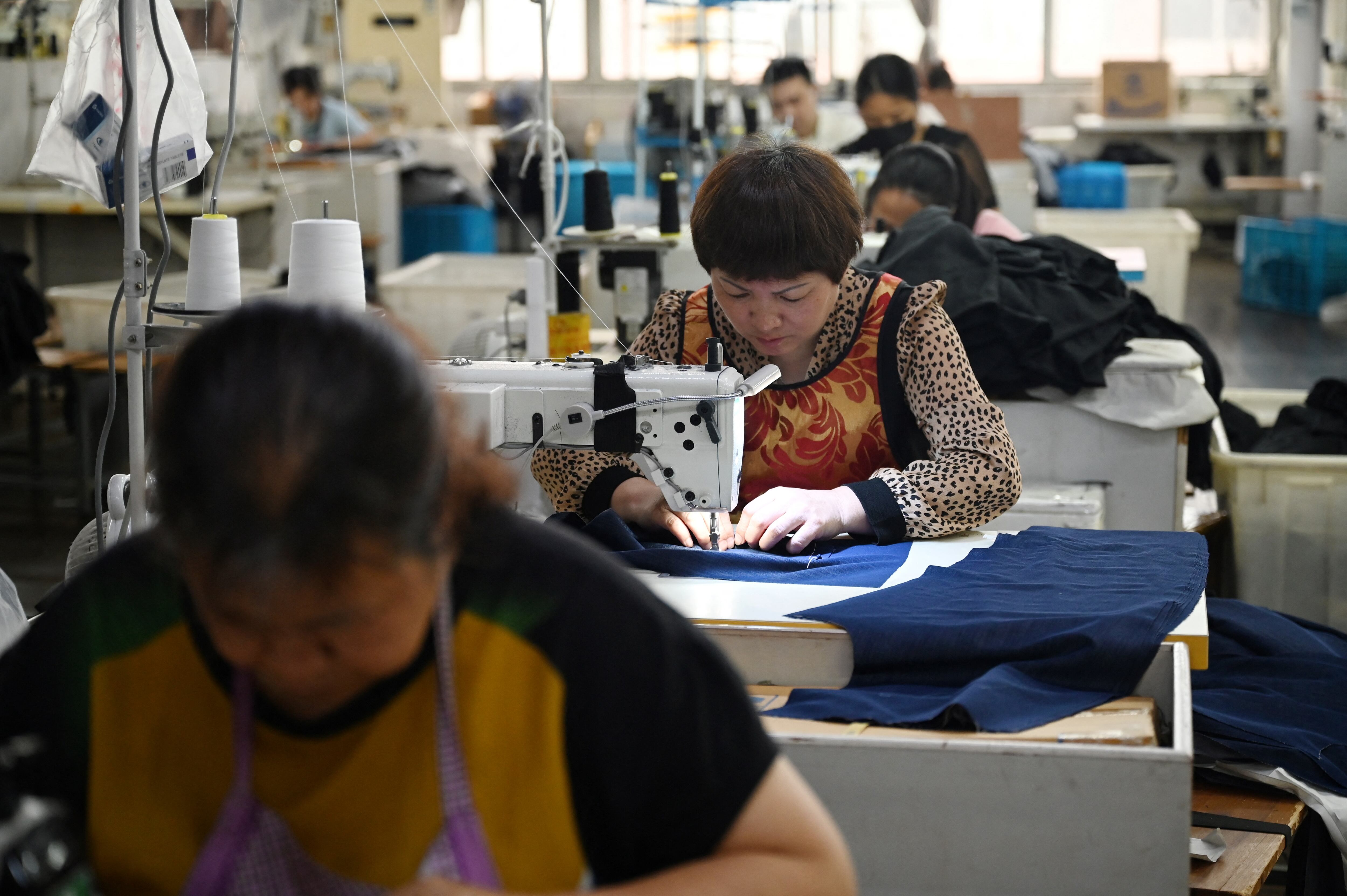 Trabajadores cosen ropa en una empresa que produce para el mercado nacional y la exportación, en un parque industrial textil de Shaoxing, provincia oriental china de Zhejiang. Fotografía: